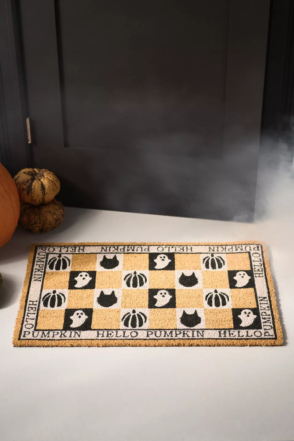 A tan, black, and white Halloween doormat