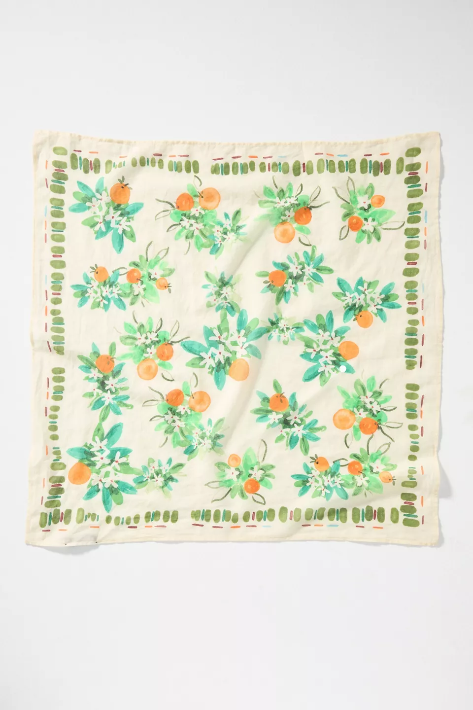 A white scarf with a green border and orange blossom plants