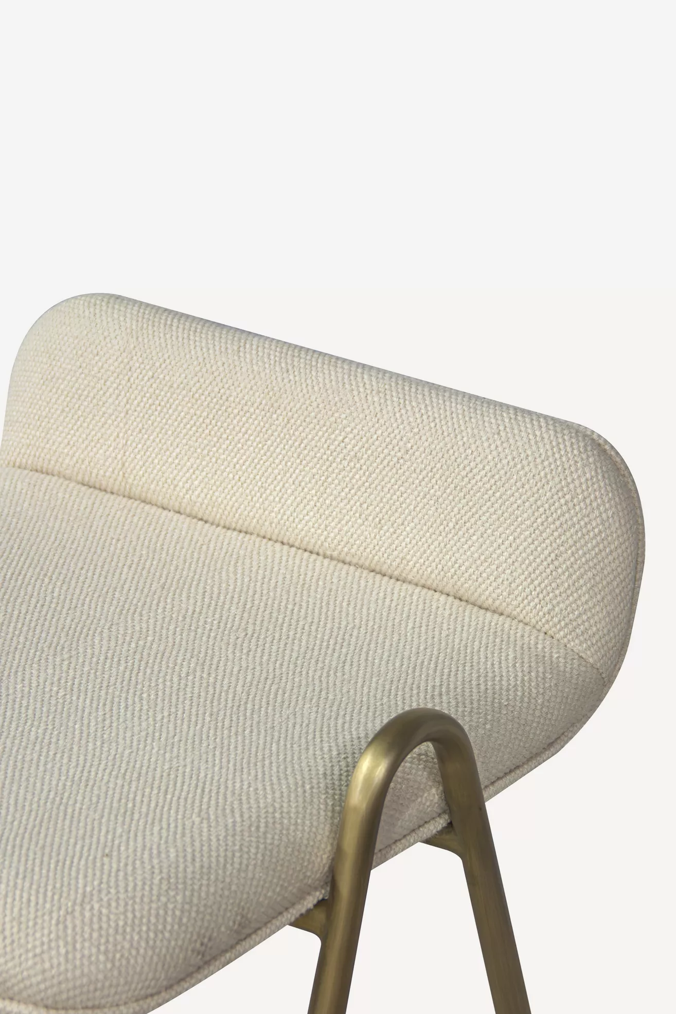 Close-up of padded cream upholstered back cushion with brass-toned metal handle