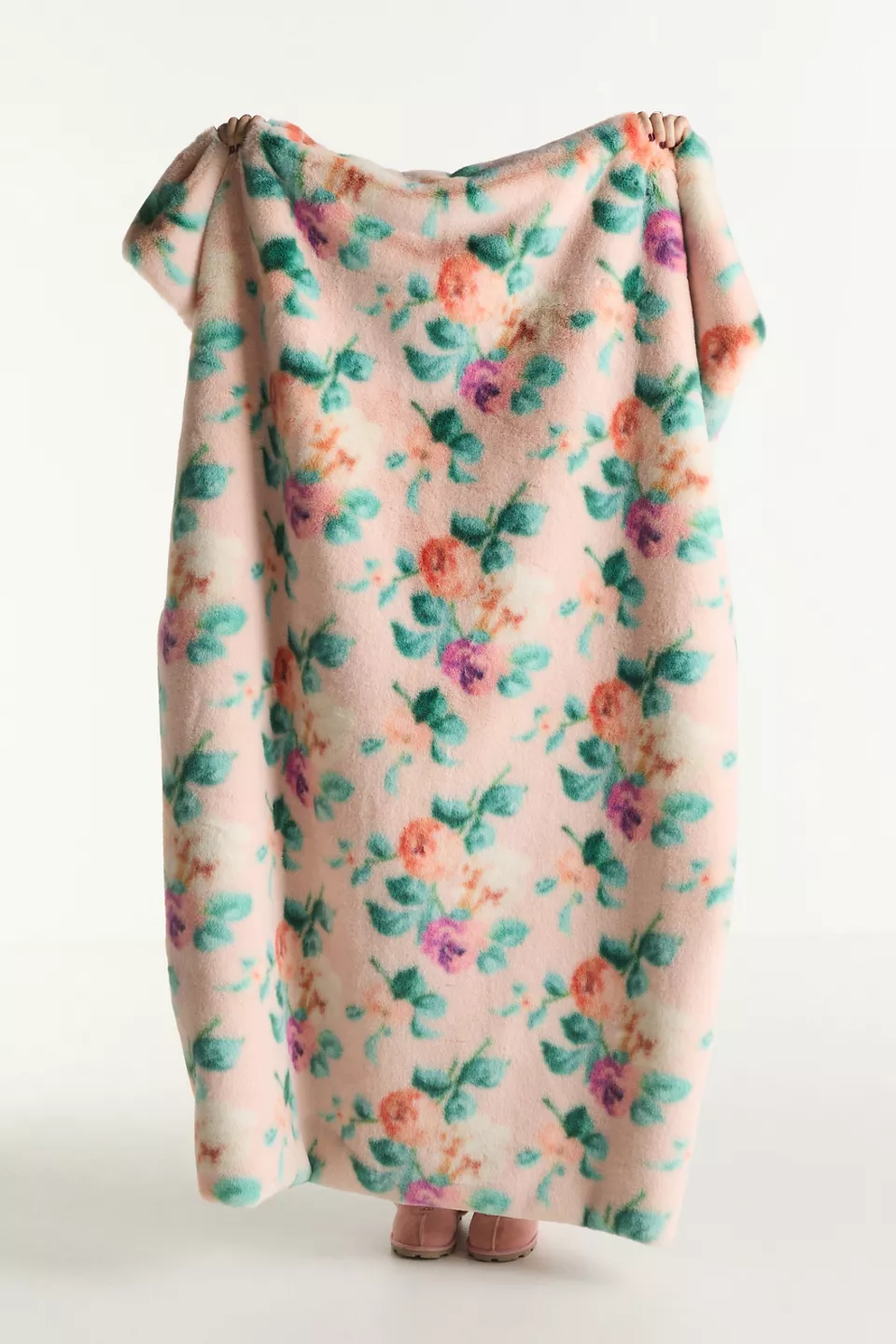 A person holding a pink floral blanket