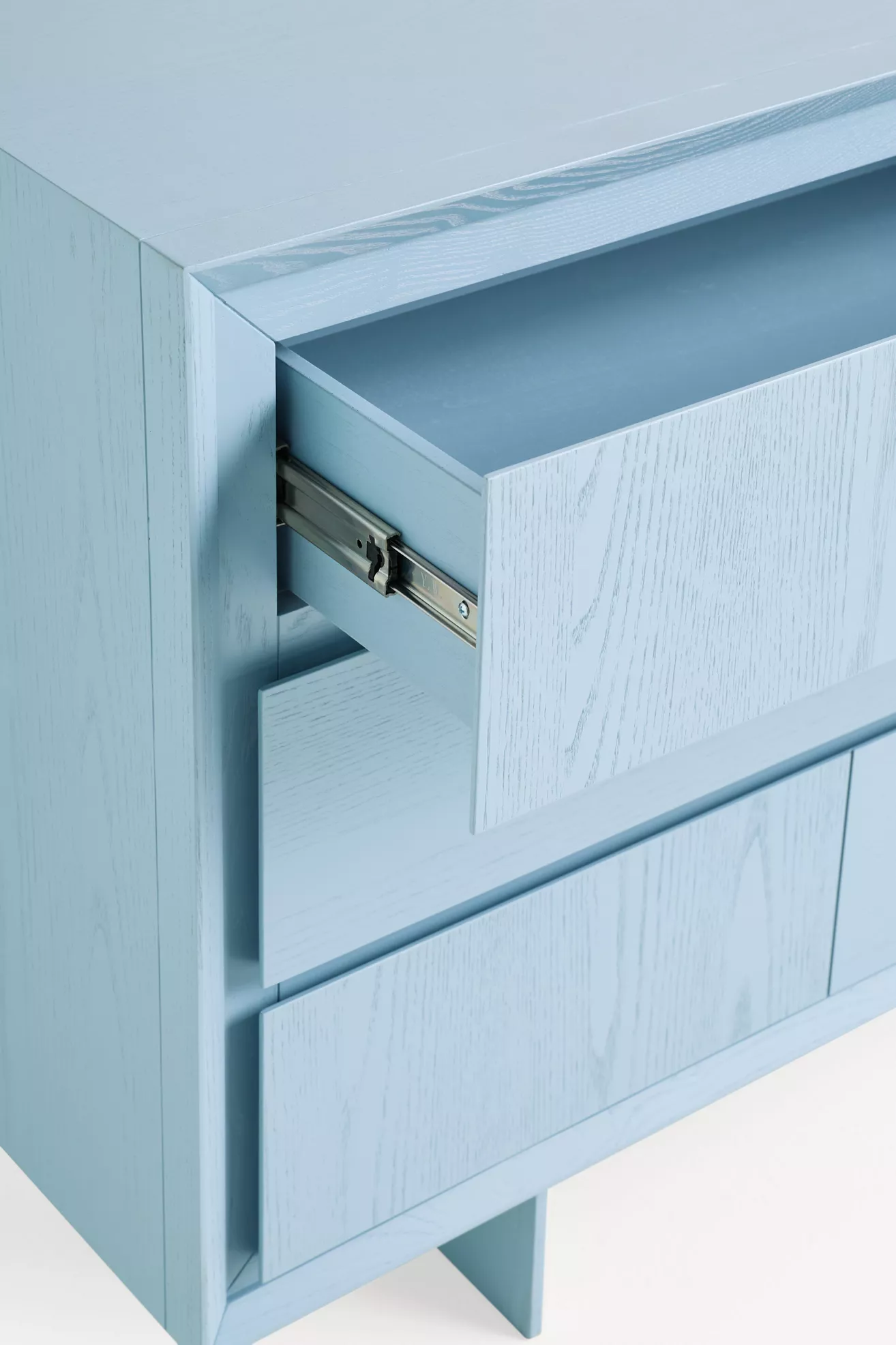 close-up of a blue six-drawer dresser with metal drawer slide