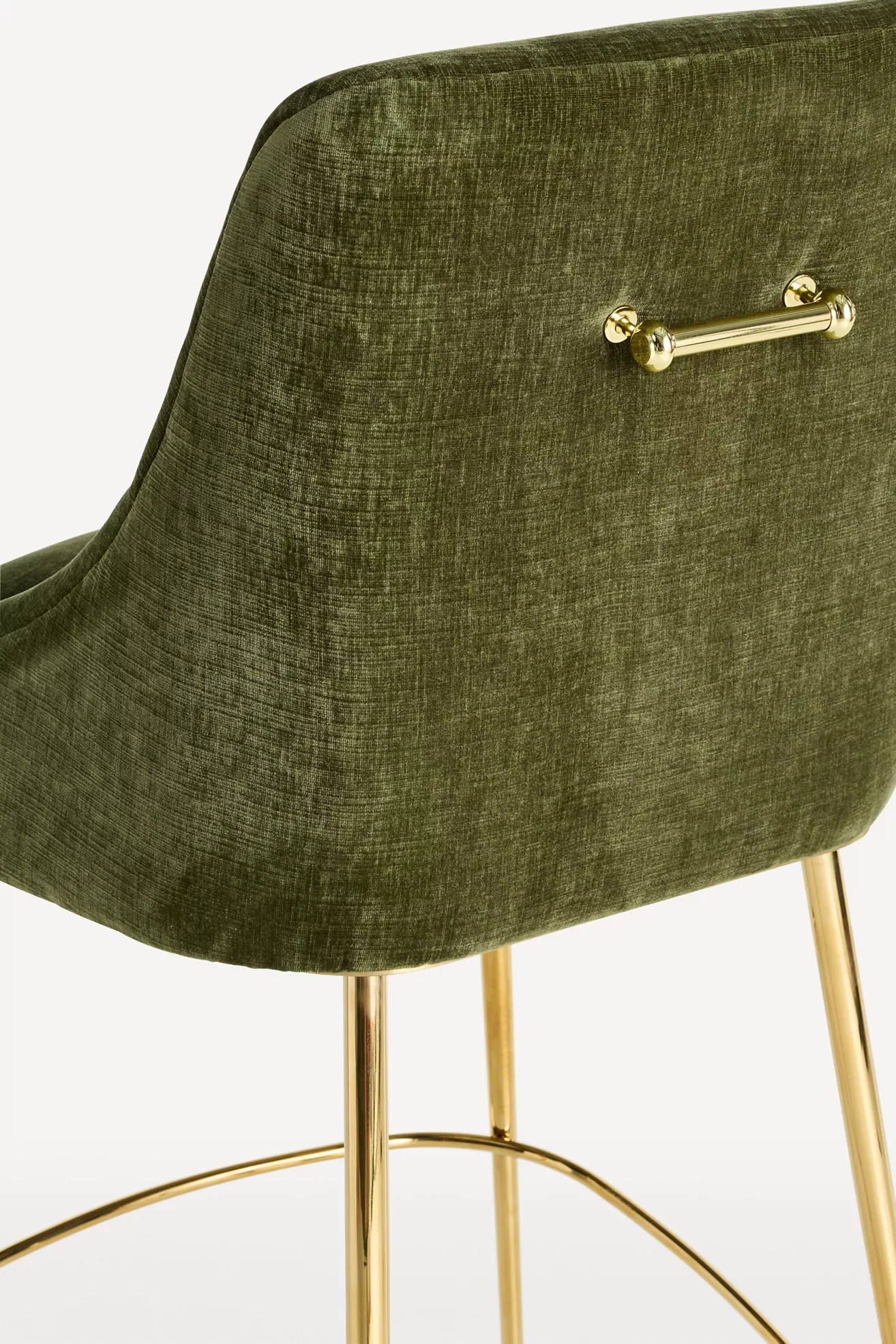 Close-up of olive green velvet upholstery with gold hardware on stool back