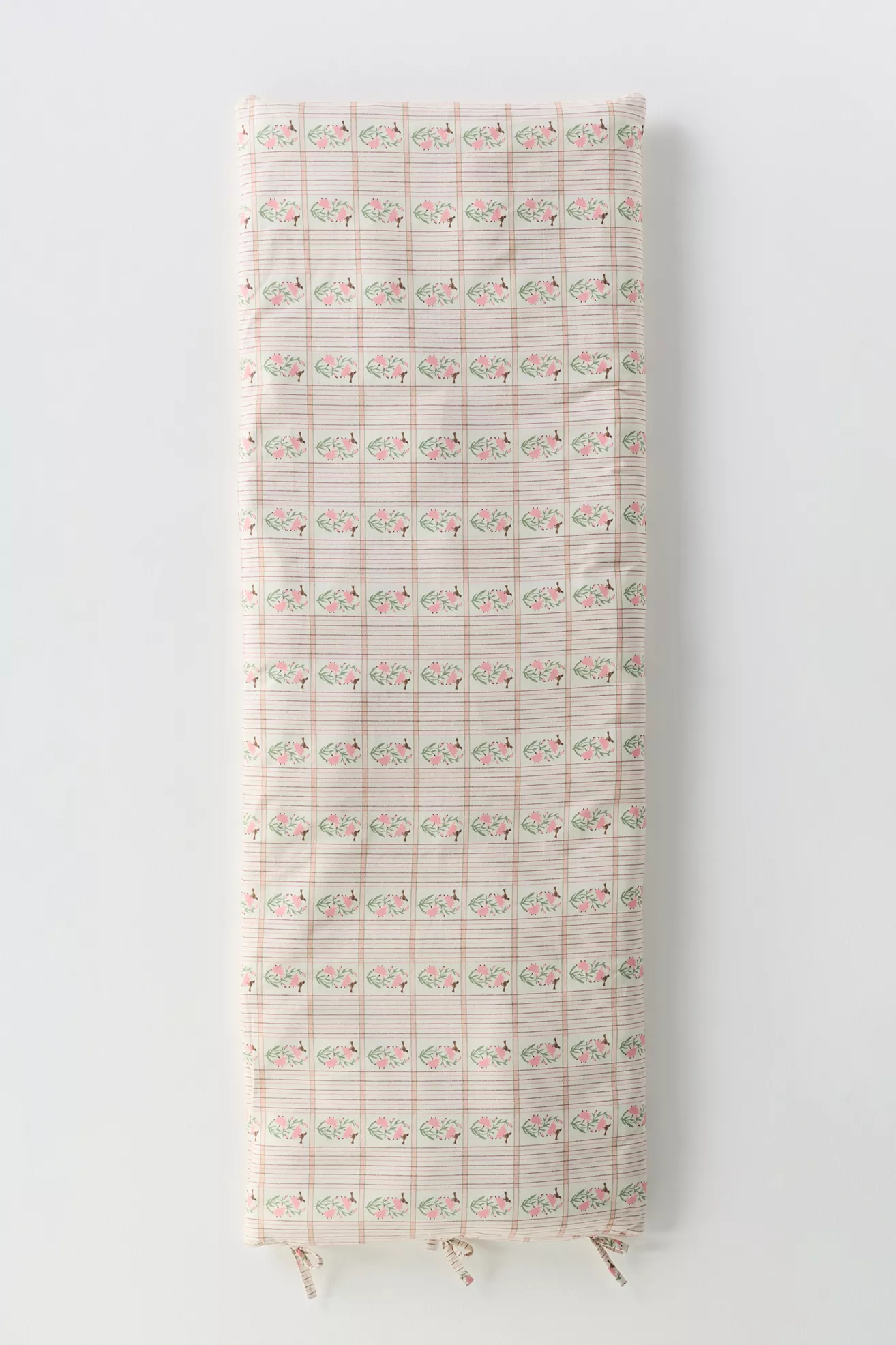 A folded cotton printed sofa topper with a pink floral pattern