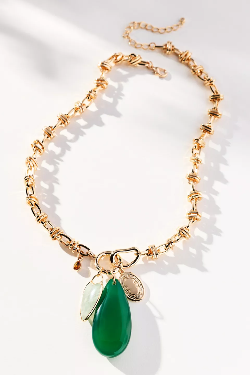 A gold statement necklace with a green charm
