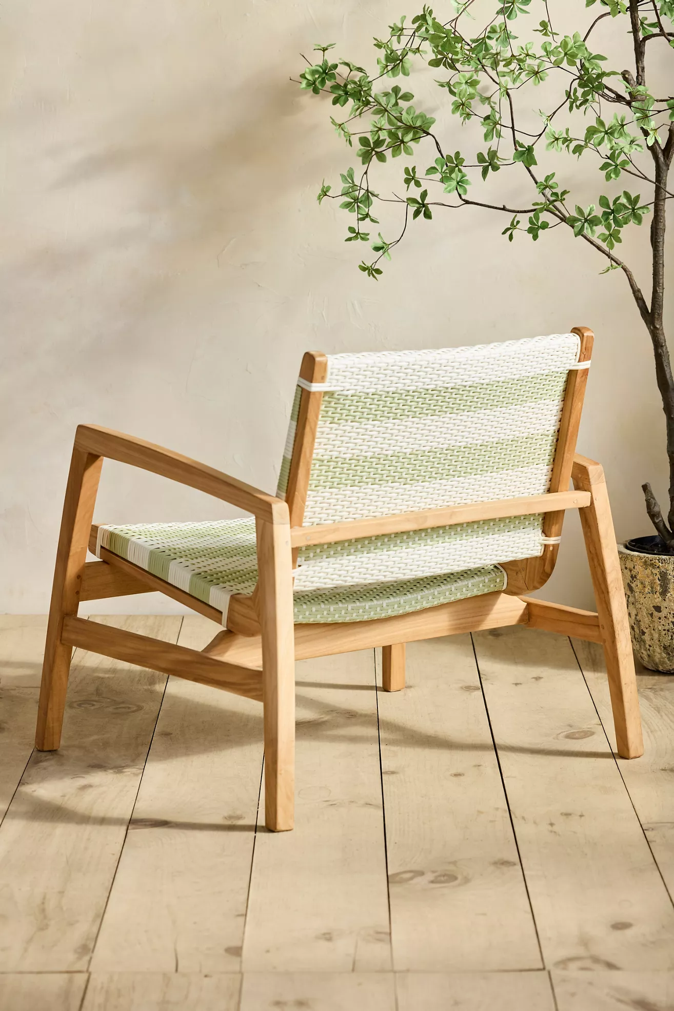 Back view of a wicker and teak lounge chair with green and white striped cushions