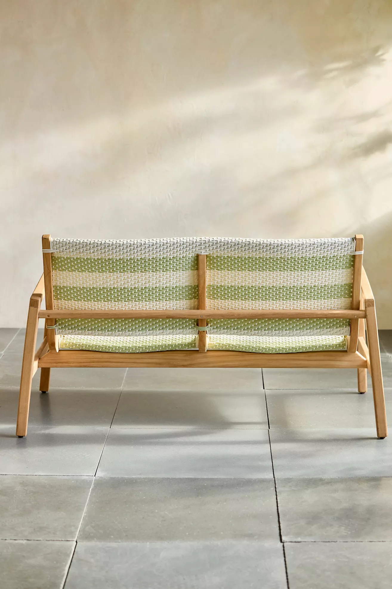Back view of green-woven sofa in outdoor setting