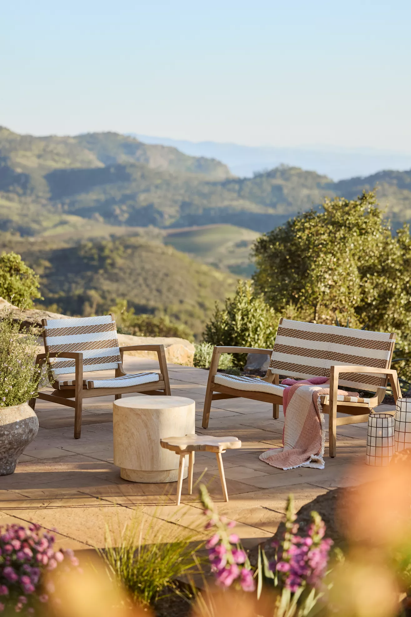 Outdoor two-seat wicker and teak sofa set with stone patio and view