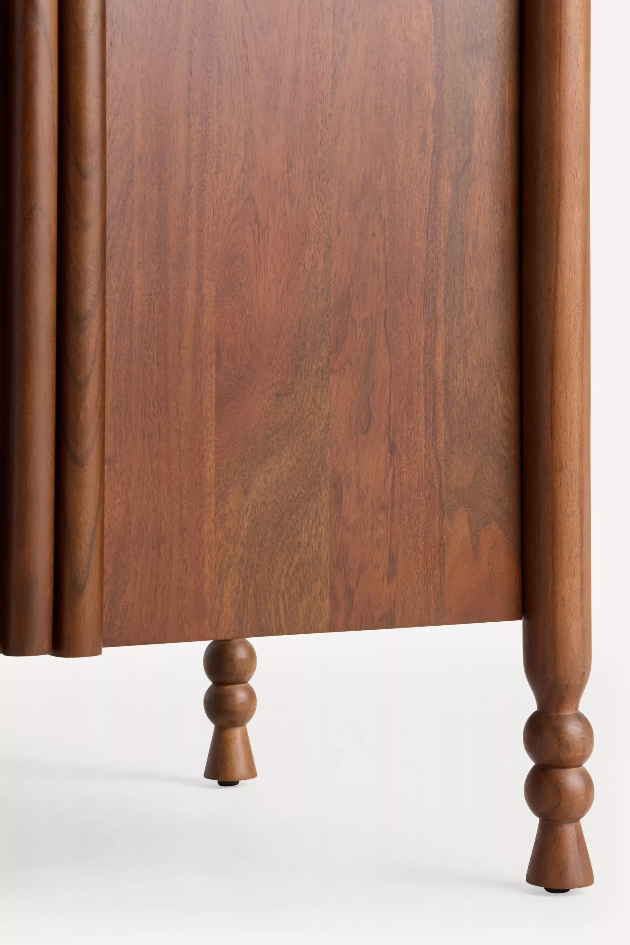 Side view of a bathroom vanity with wood cabinet doors and turned legs.