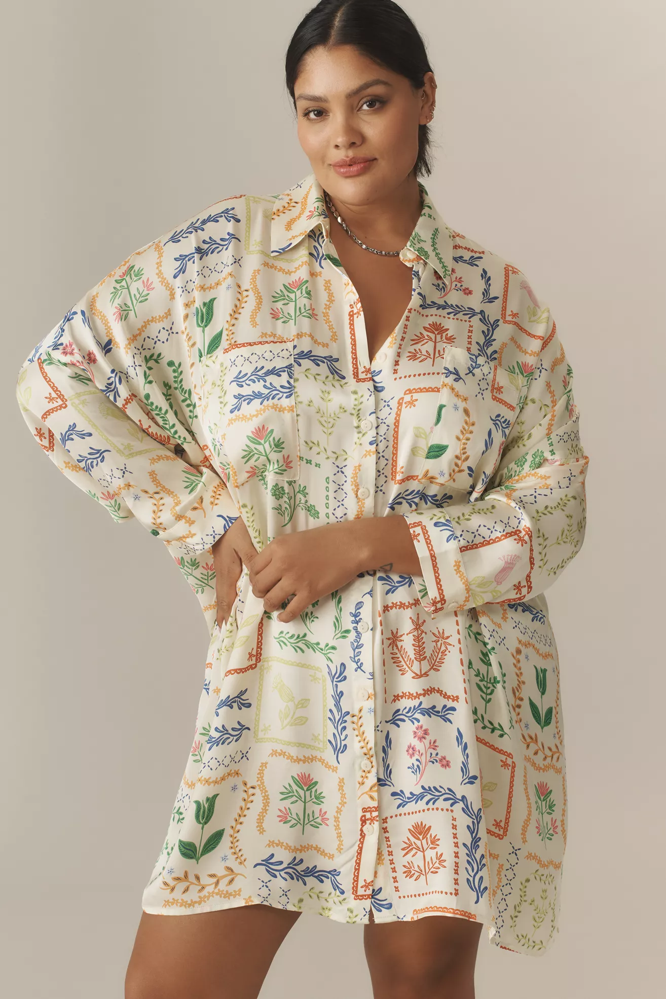 A plus-size, white, button-up mini dress with a multicolor graphic floral print
