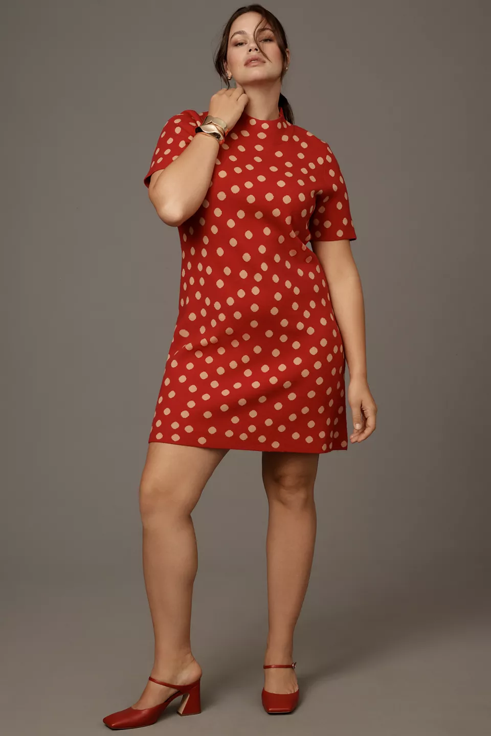 A plus-size, red, mock-neck mini dress with tan polka dots