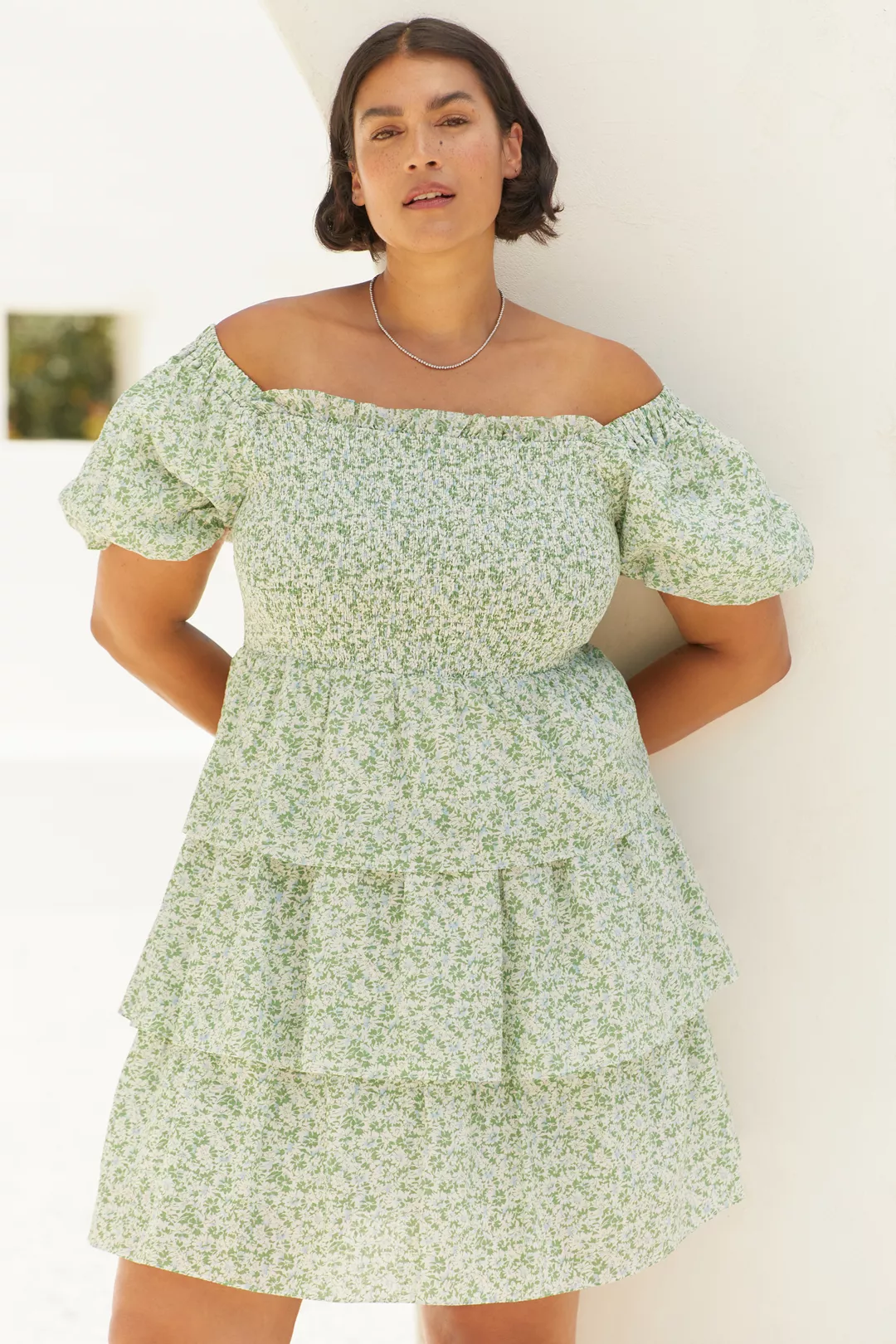 A plus-size, green-and-white floral, puff-sleeve, ruffled mini dress