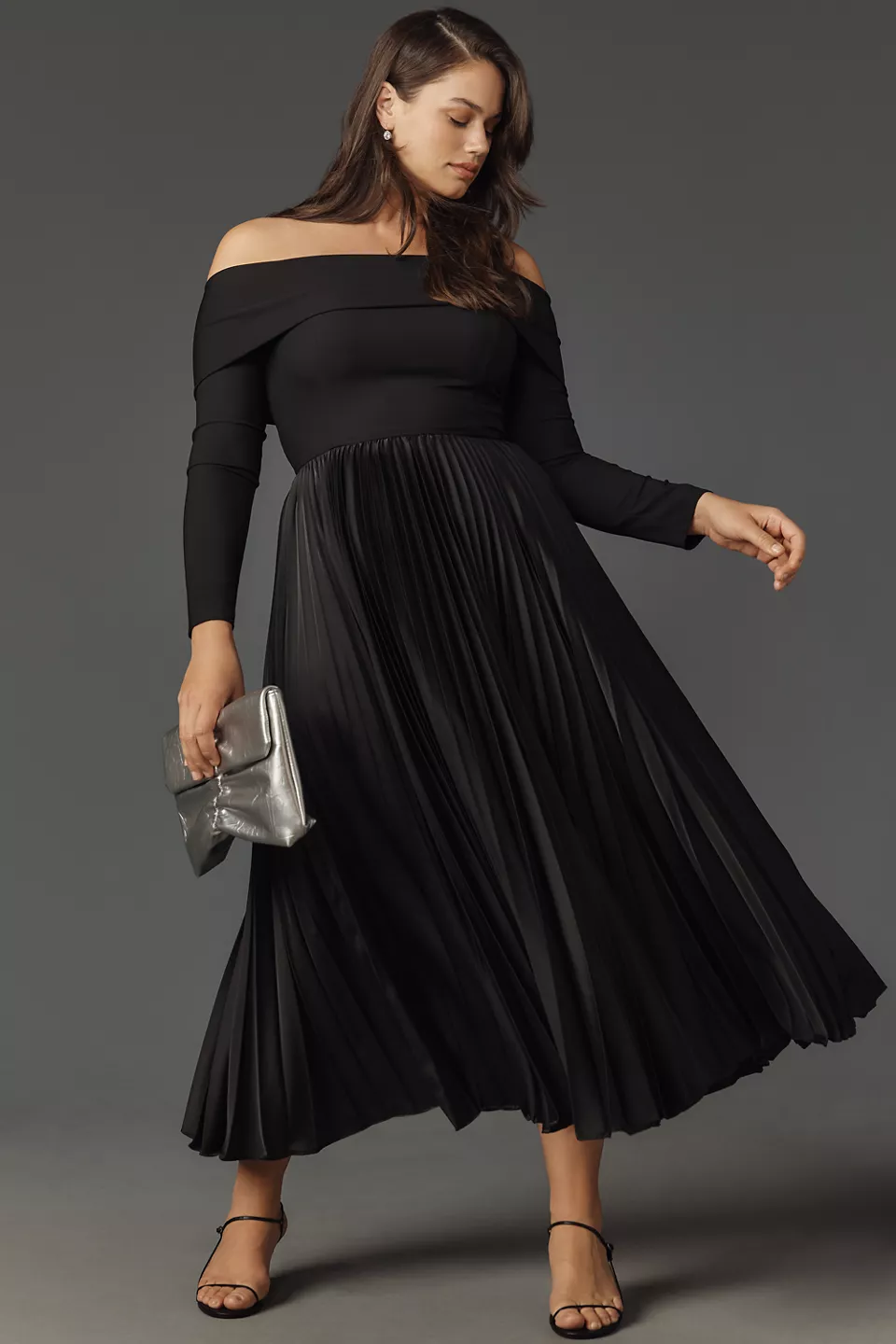 A plus-size, black, off-the-shoulder cocktail dress with a pleated skirt
