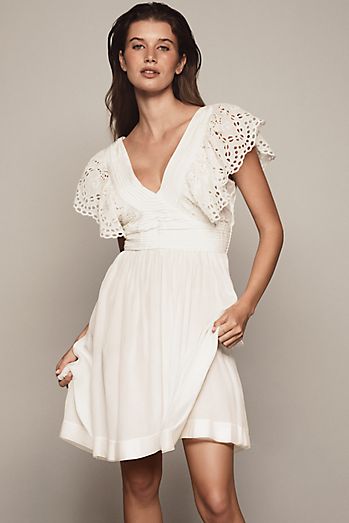 anthropologie white dress By Embroidered V-Neck Ruffled Mini Beautiful cutwork detailing and contrast embroidery depicting floral motifs line the trims White Dresses | Mini, Midi