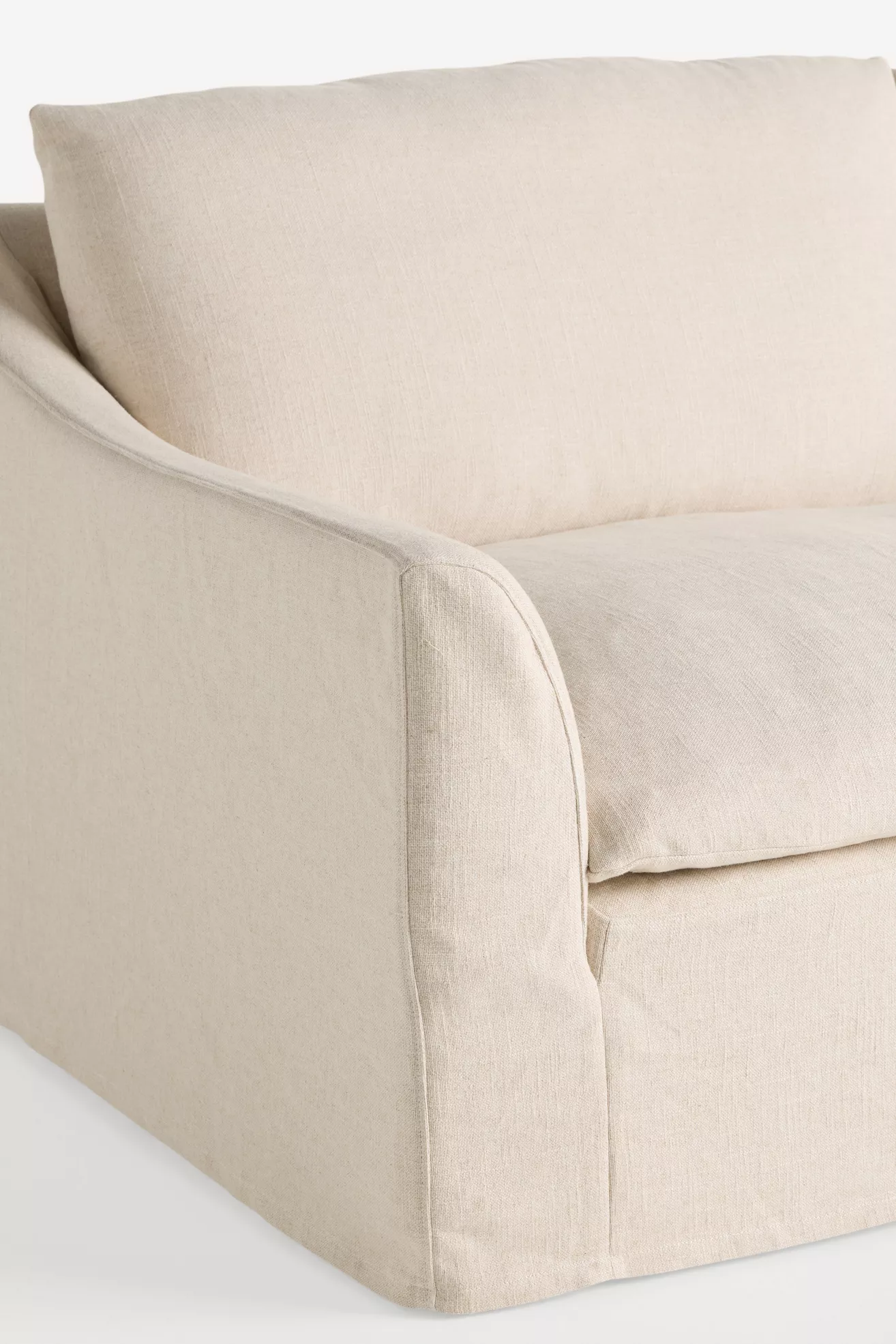 Close-up of arm and cushion seam on beige slipcovered sofa