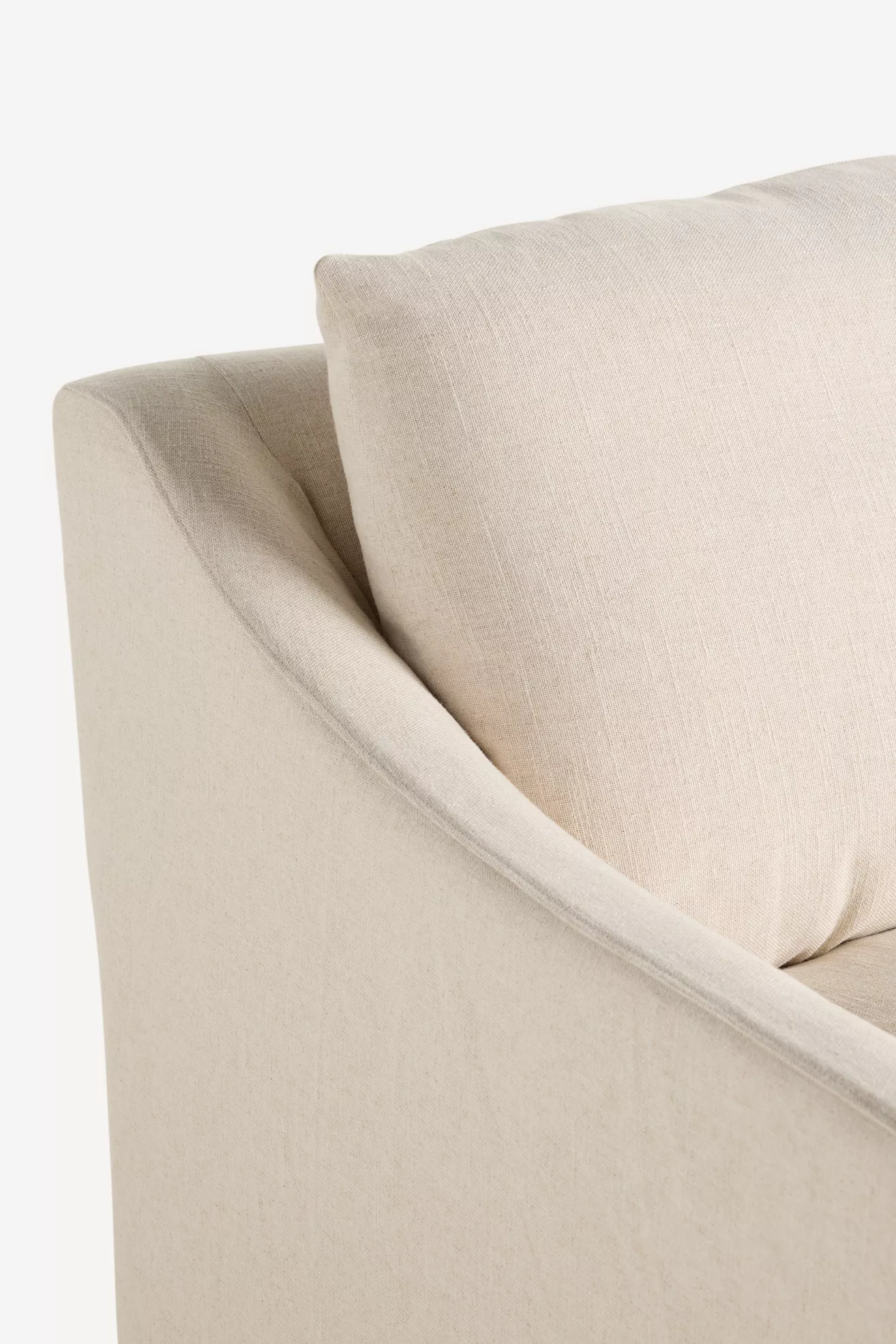 Close-up of back cushion and arm on beige slipcovered sofa