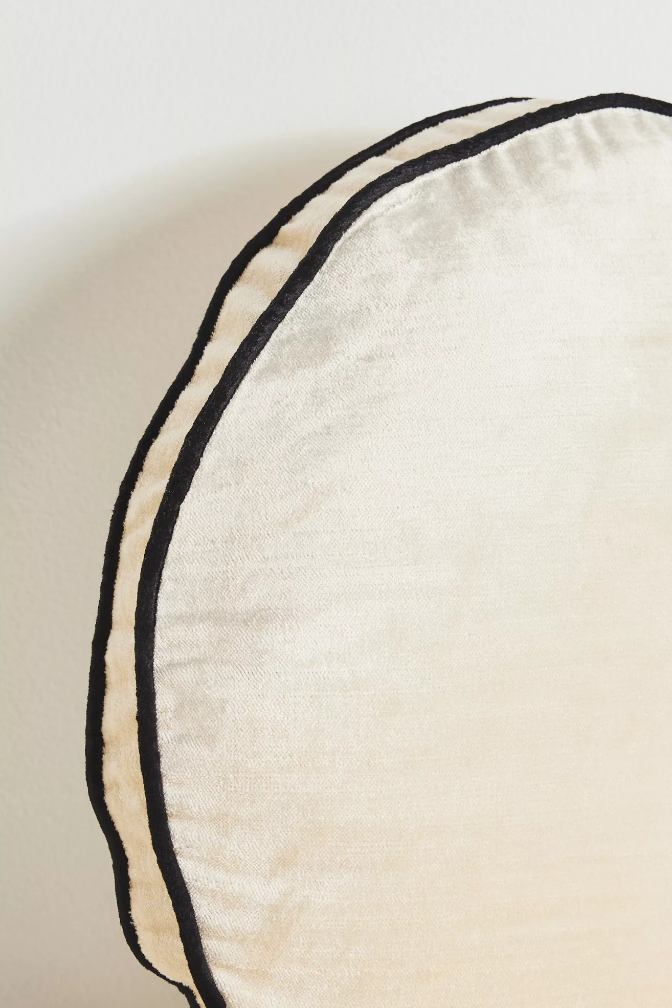 Close-up of the black piping along the edge of cream velvet fabric