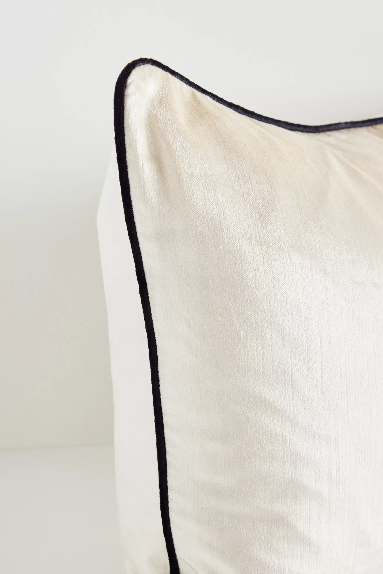 Close-up of velvet texture and piping on cream pillow