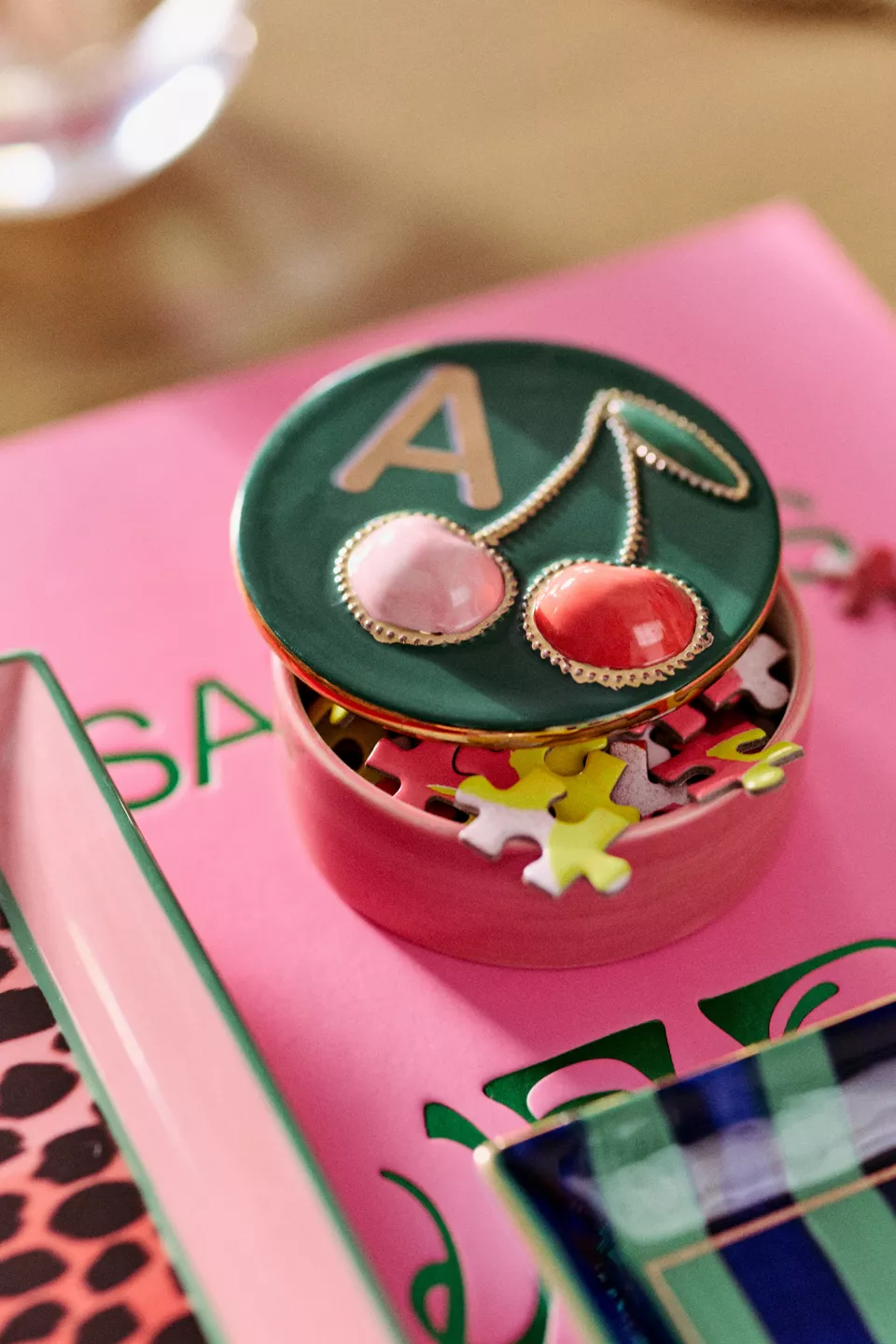 A pink and green trinket box with puzzle pieces inside