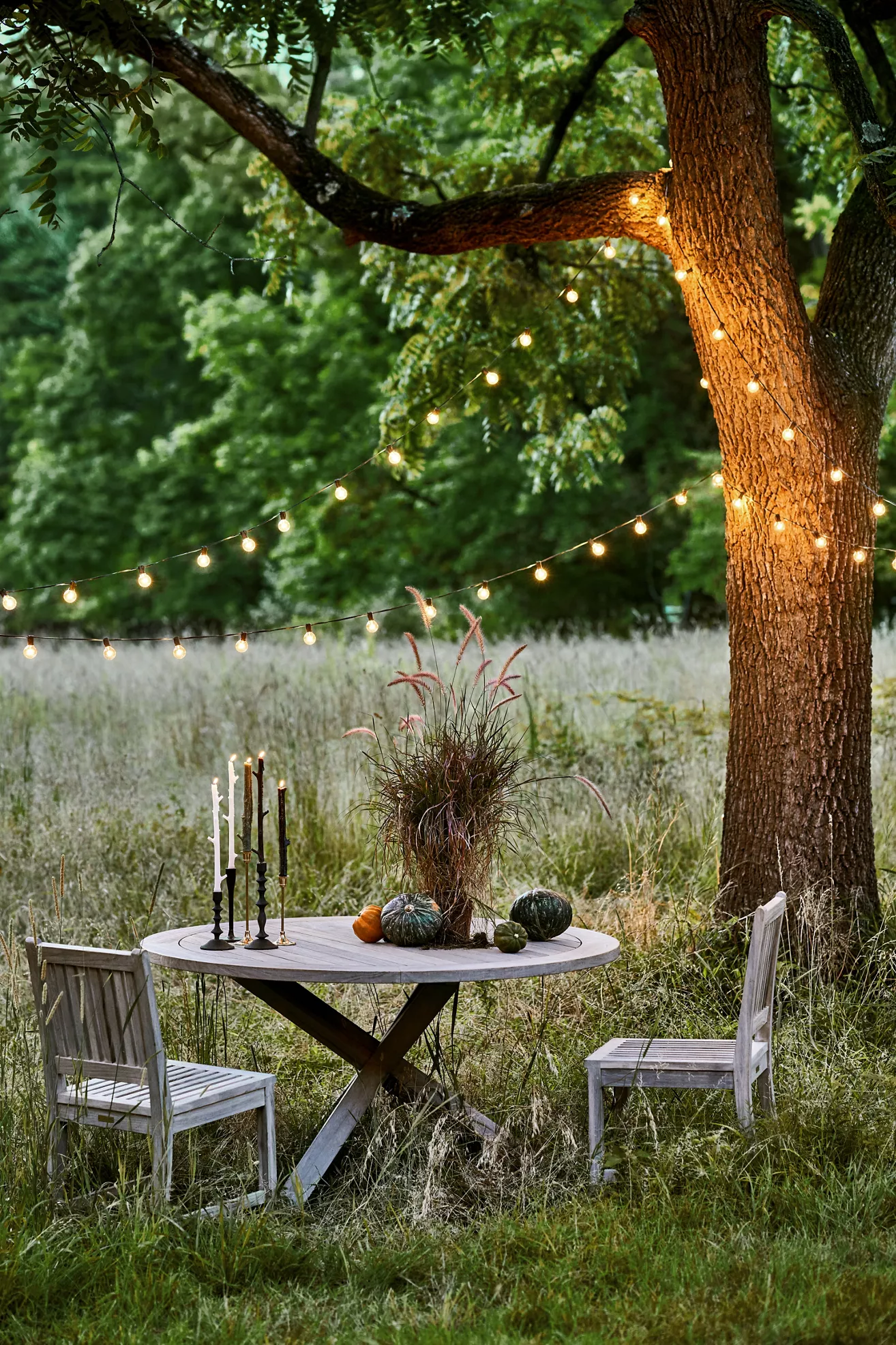 Outdoor round dining table with cross legs under string lights