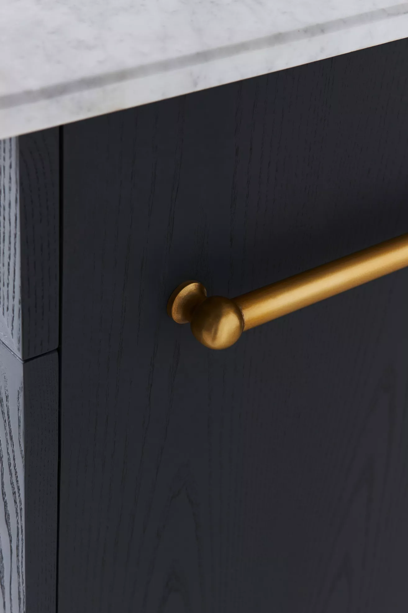 Brass towel bar mounted on navy cabinet