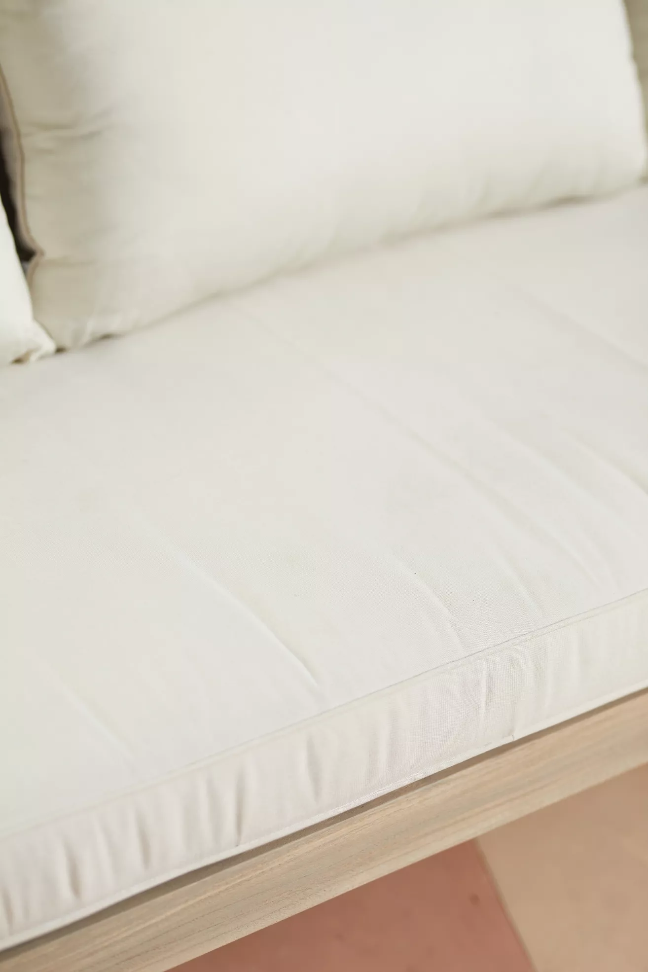 Close-up of white seat cushion on teak outdoor sofa