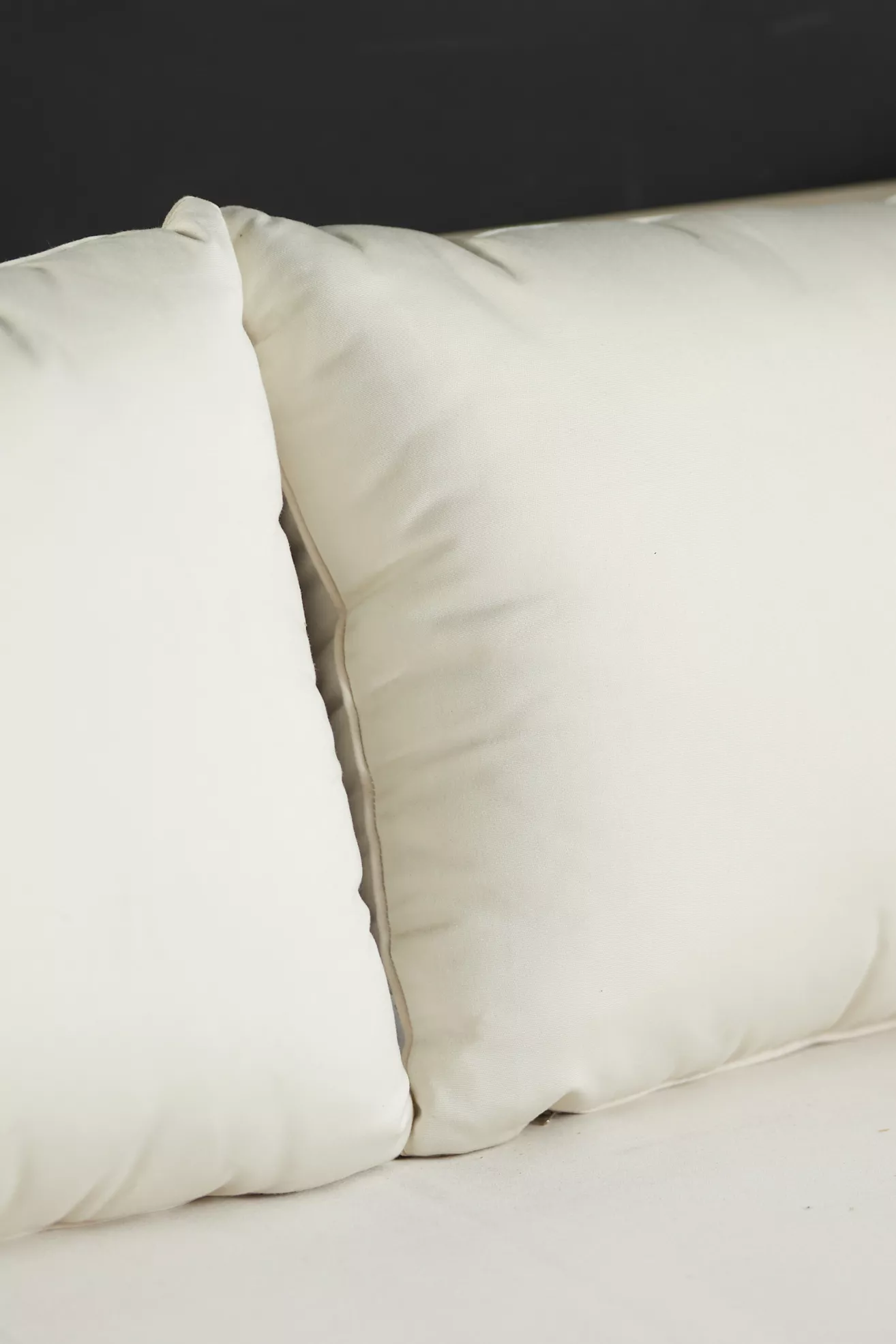 Close-up of white back cushion on teak sofa