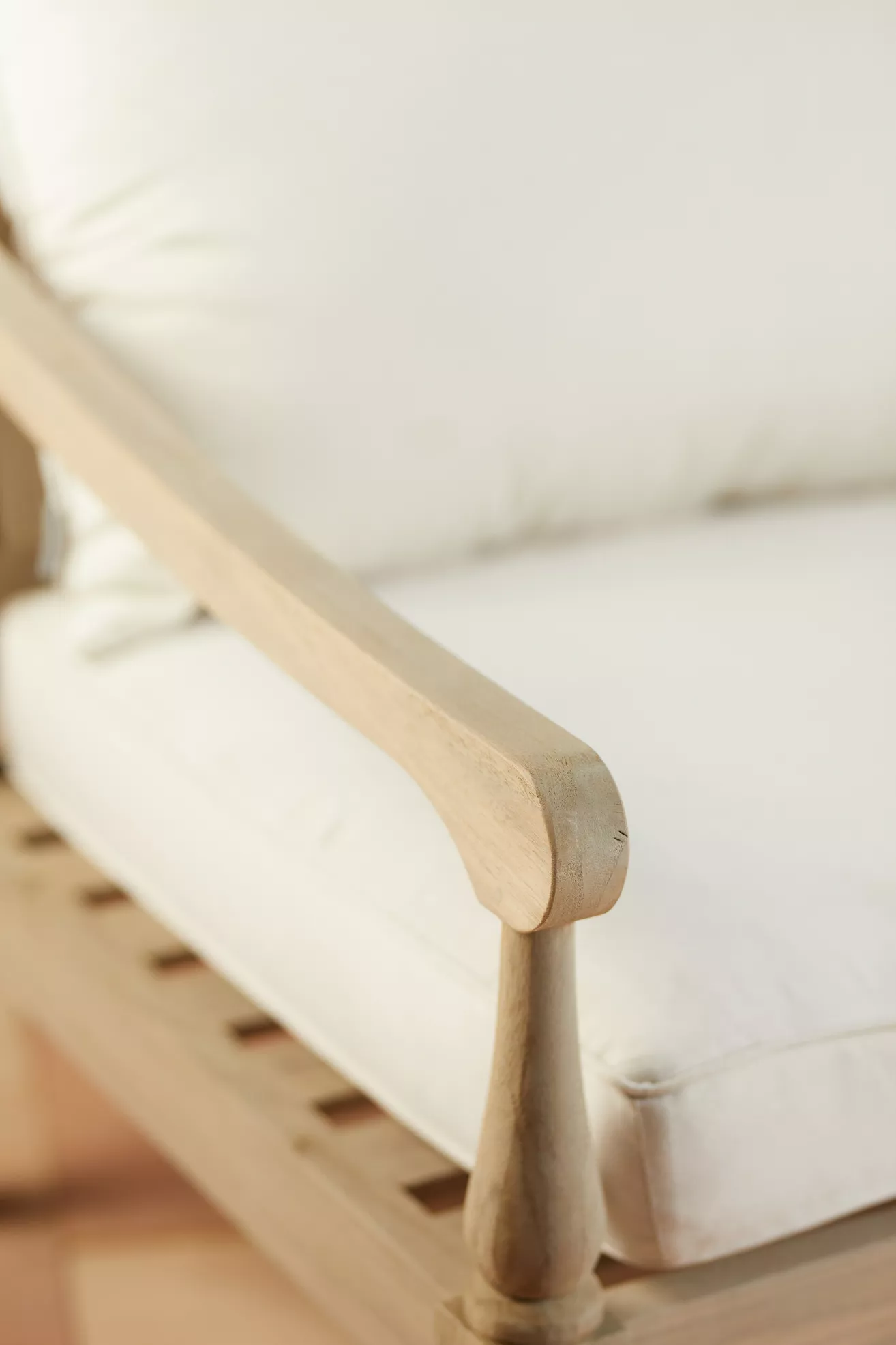Close-up of teak arm and edge of white cushion