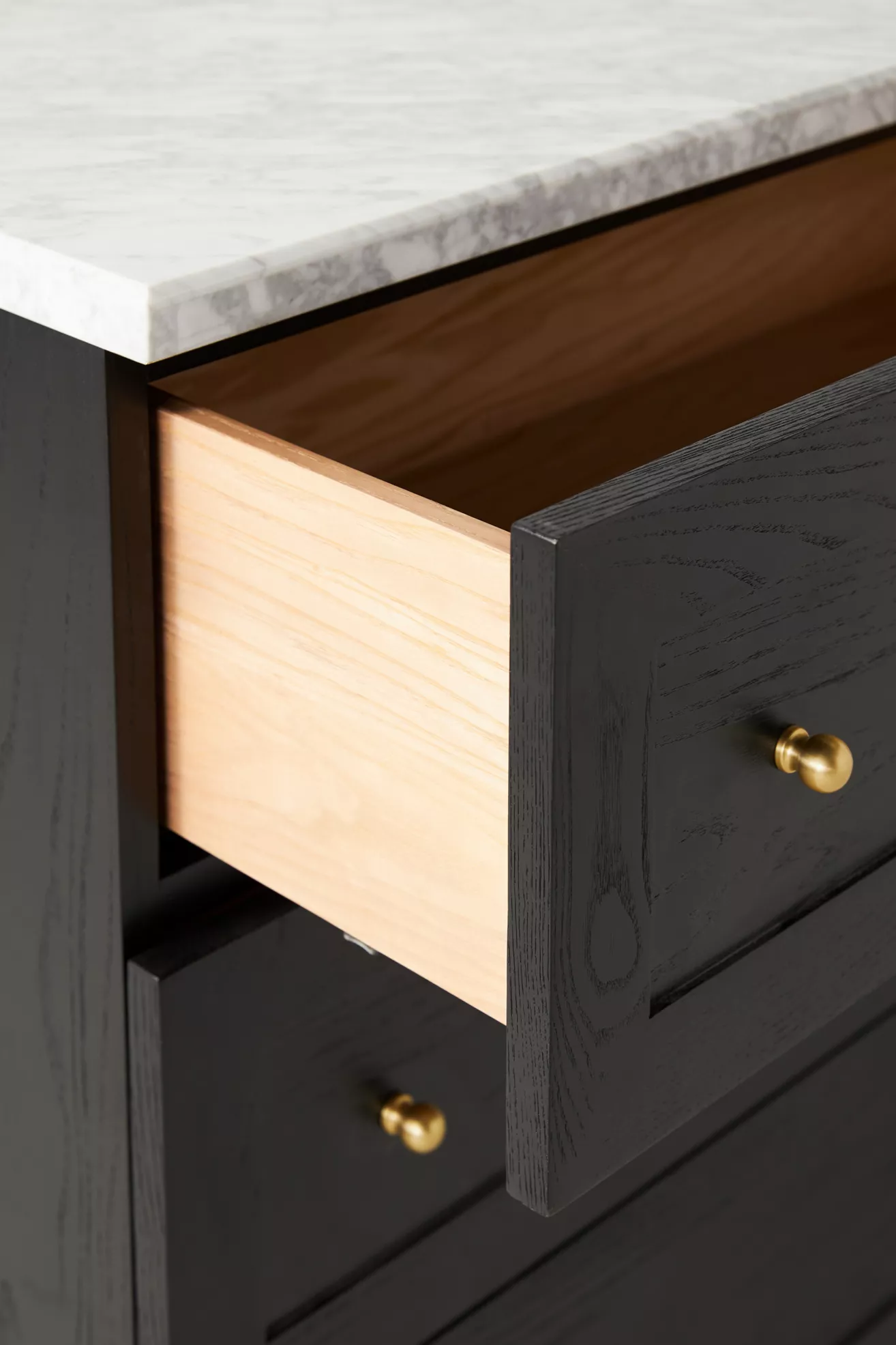 Close-up of drawer with gold knob and marble top edge