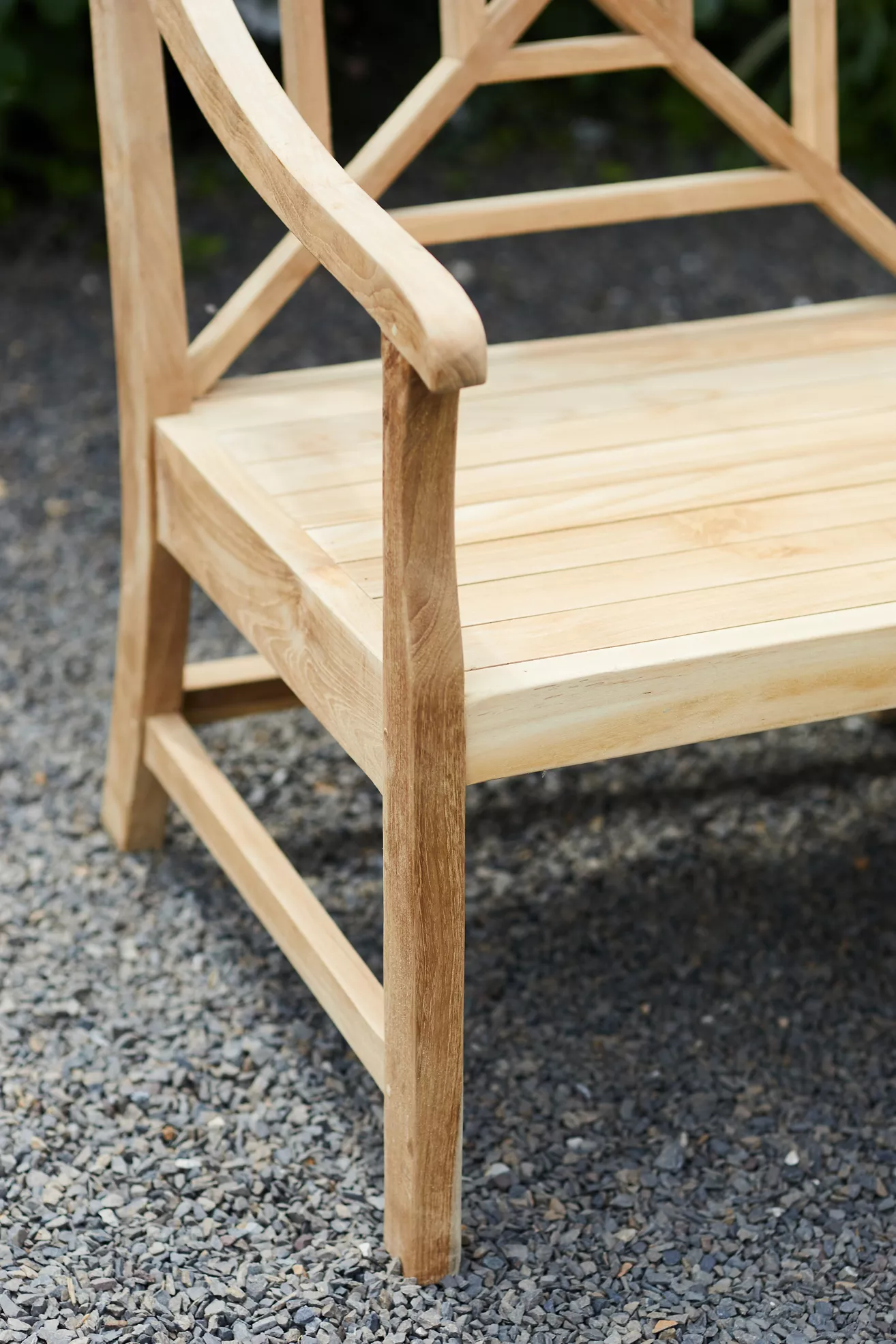 Close-up of armrest and edge of teak bench showing curved arm and joints