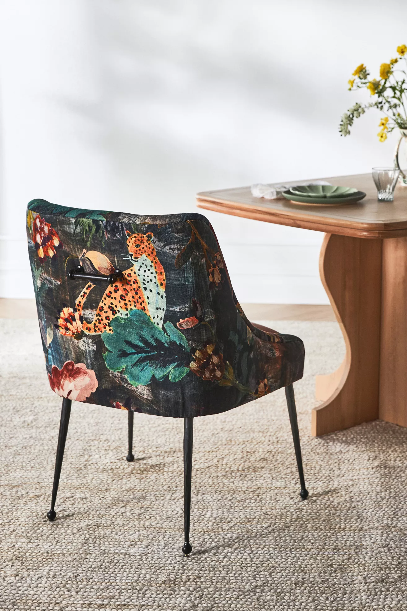 Close-up of a velvet dining chair with a dark botanical print