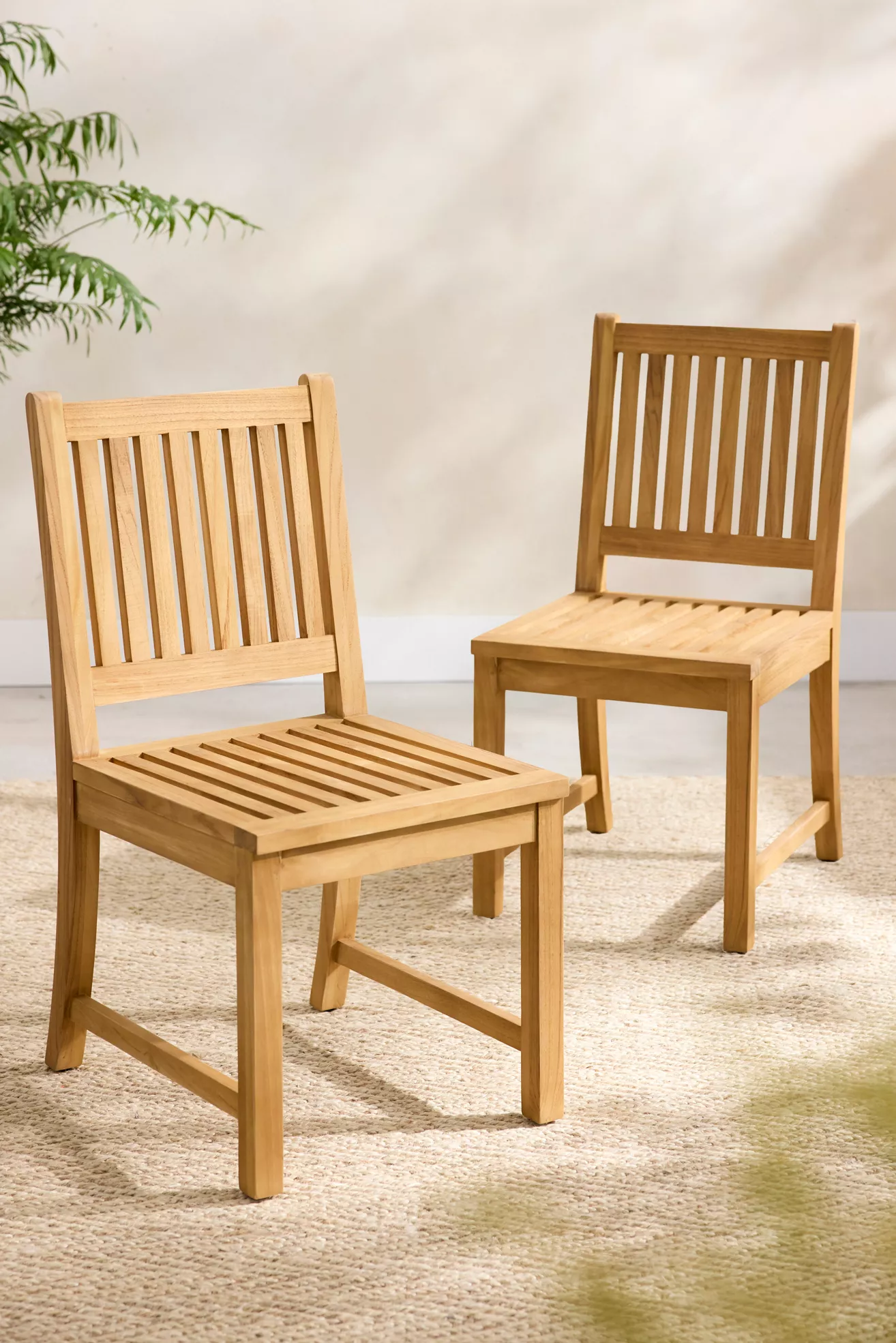 Two teak slatted chairs arranged in a studio setting