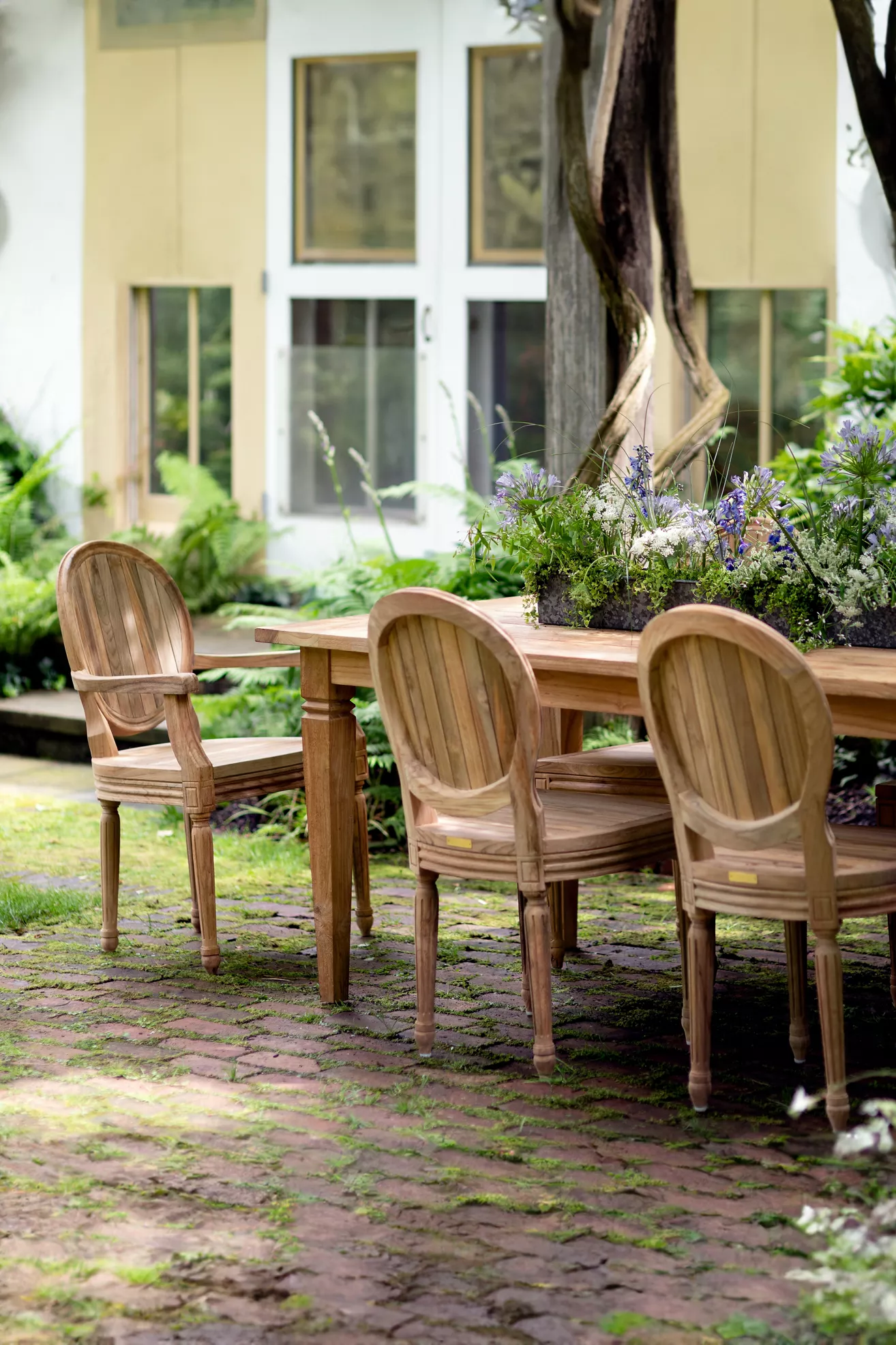 Set of four light wood oval-back chairs around a dining table outdoors