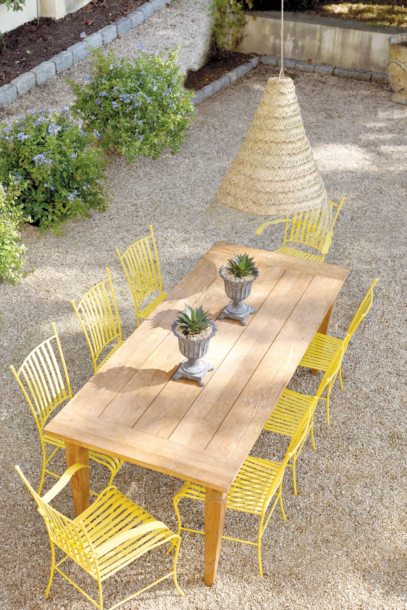 Outdoor dining table in gravel setting with yellow chairs