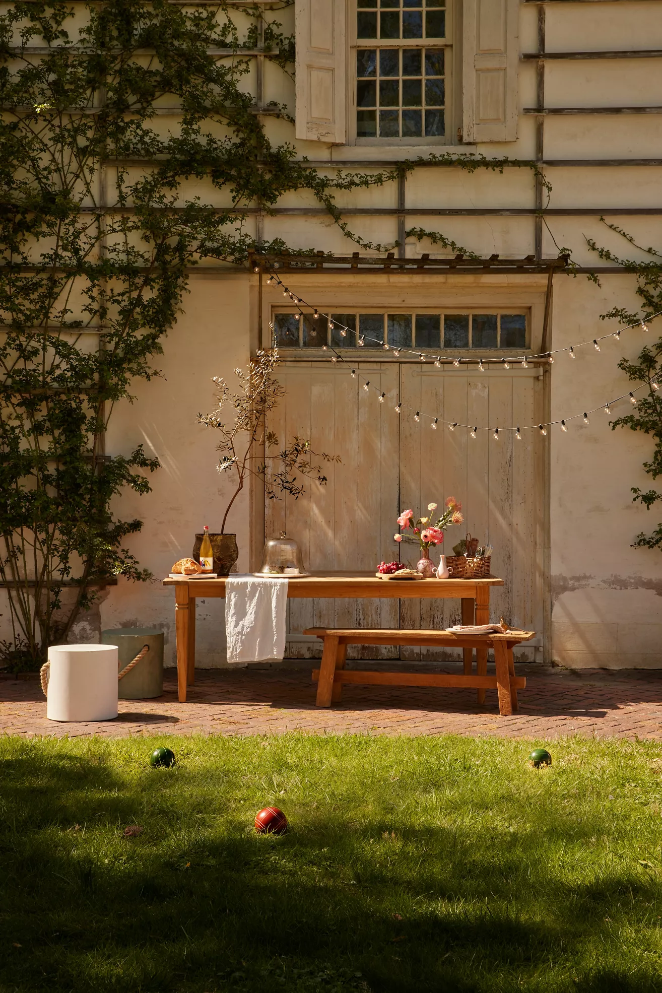 Wood dining table outdoors with string lights and palm ivy