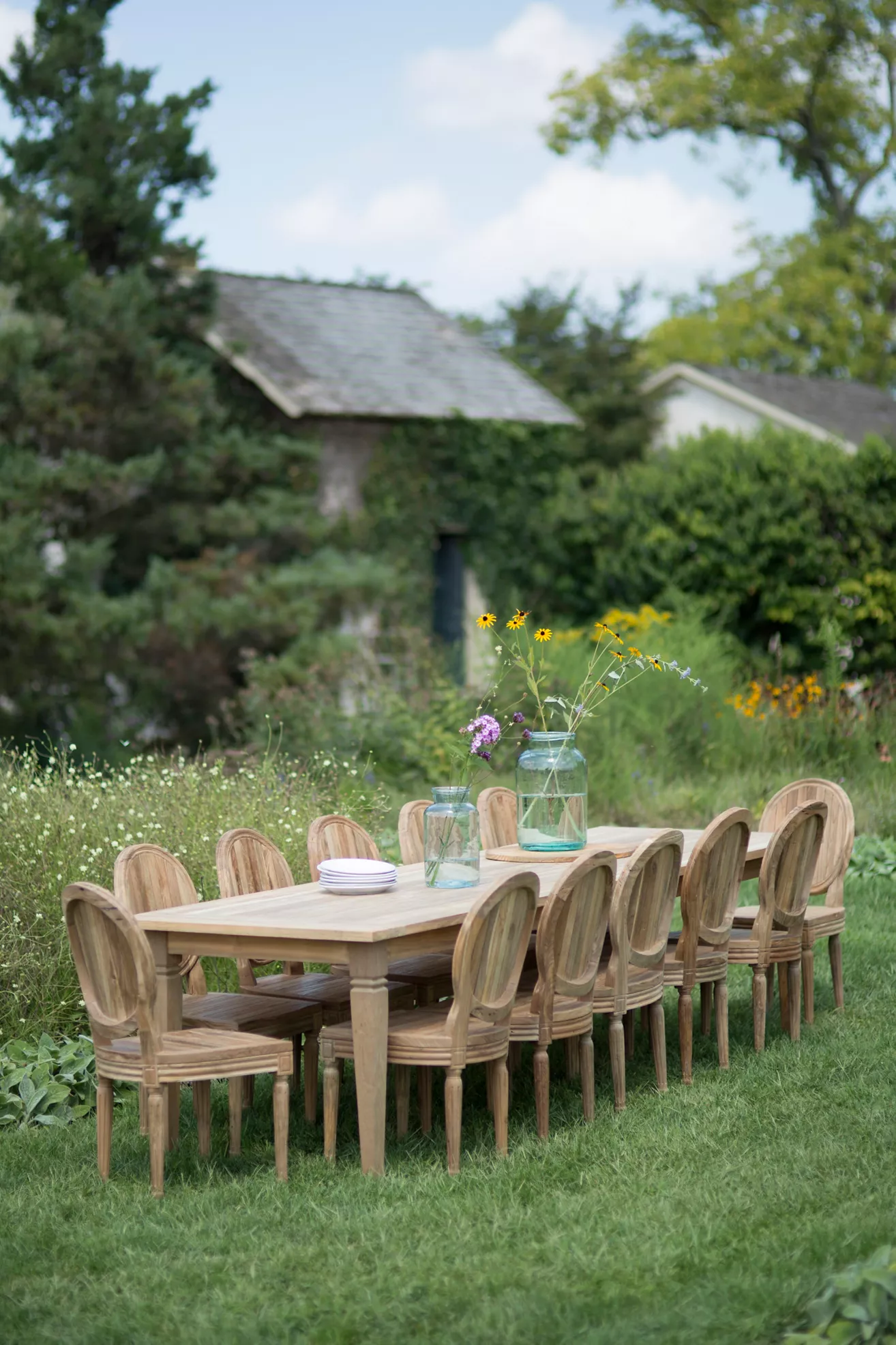 Wood dining table with matching chairs set outdoors with flowers