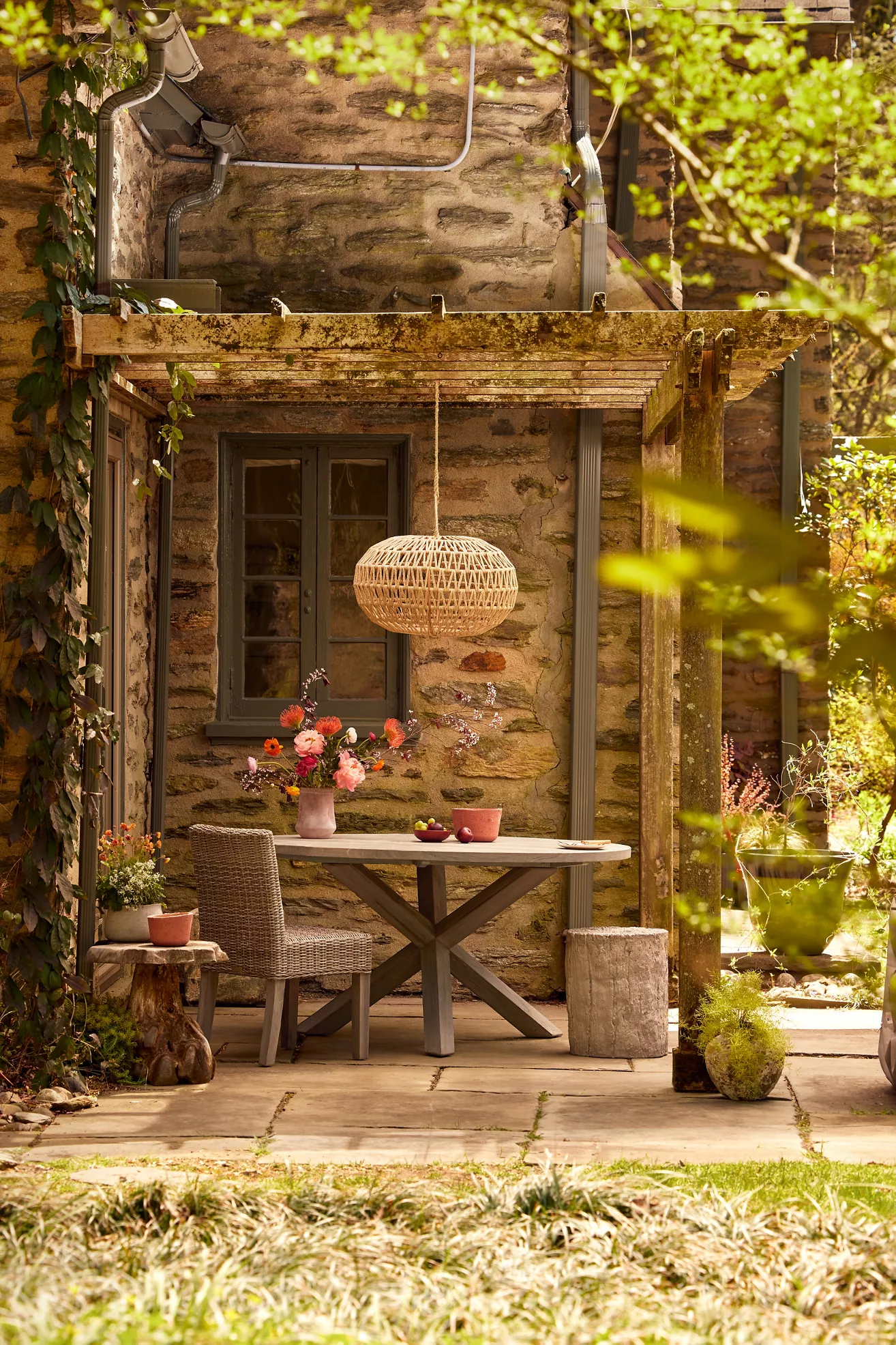 Outdoor dining table with matching wicker chairs under pergola
