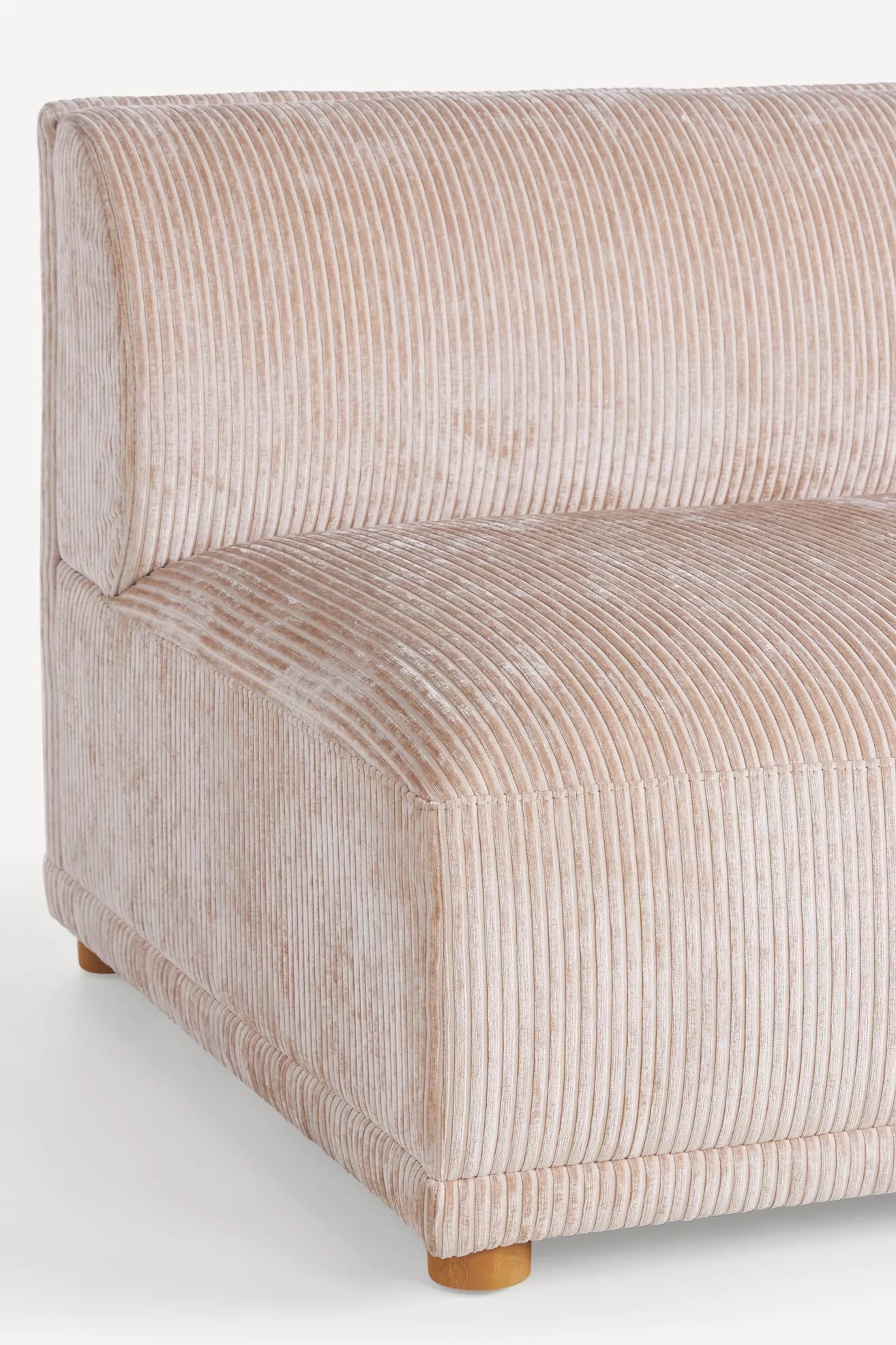 Close-up of the sofa corner showing corduroy ribbed fabric and rounded edge.