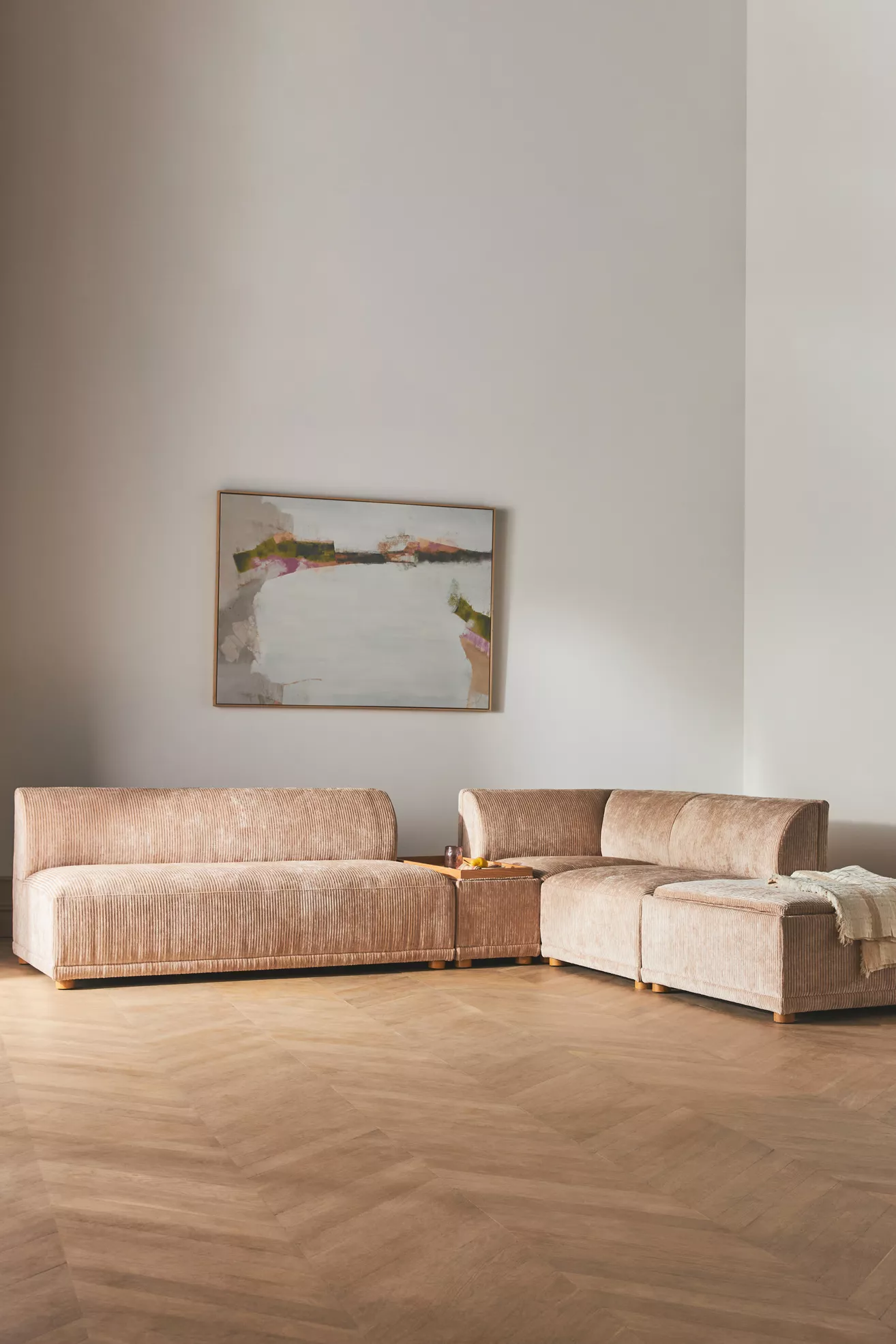 Light beige corduroy modular sofa and ottoman configuration in an interior setting.