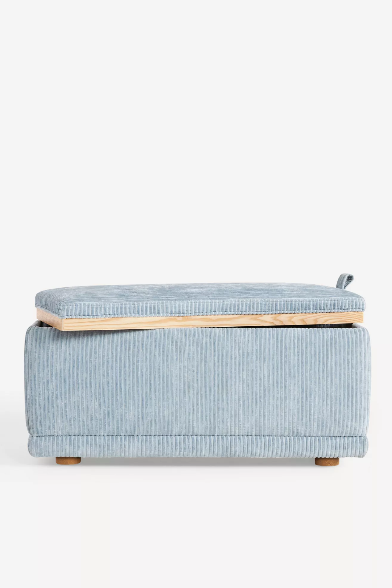 Rear/side view of light blue corduroy storage ottoman showing lid edge and wooden base.