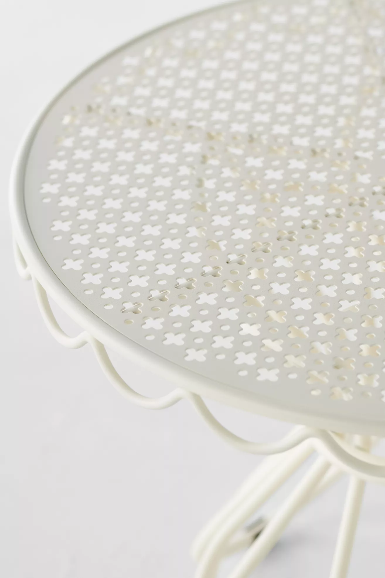 Close-up of the round perforated tabletop showing floral cutouts and metal edge