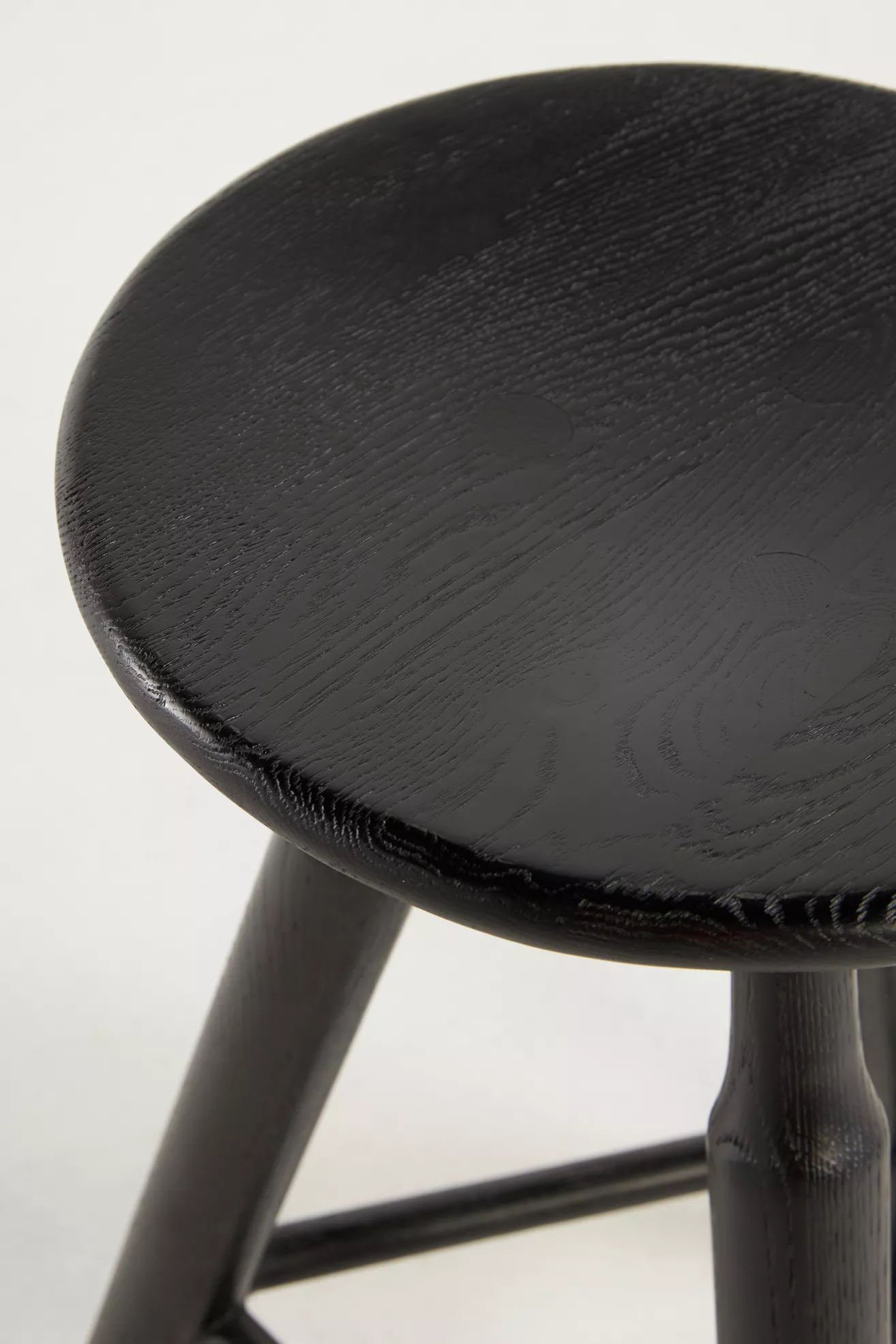 Close-up of black stool round seat showing wood grain and finish