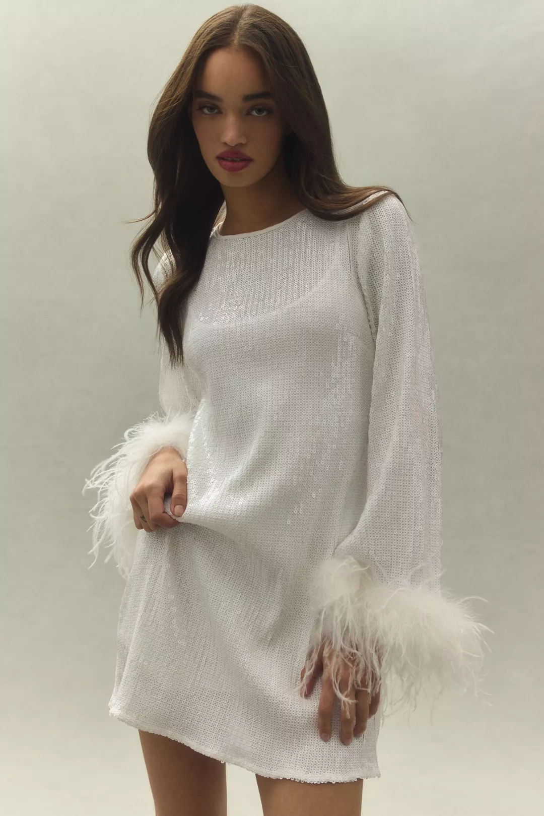 A long-sleeve white sequin mini dress with feather trim