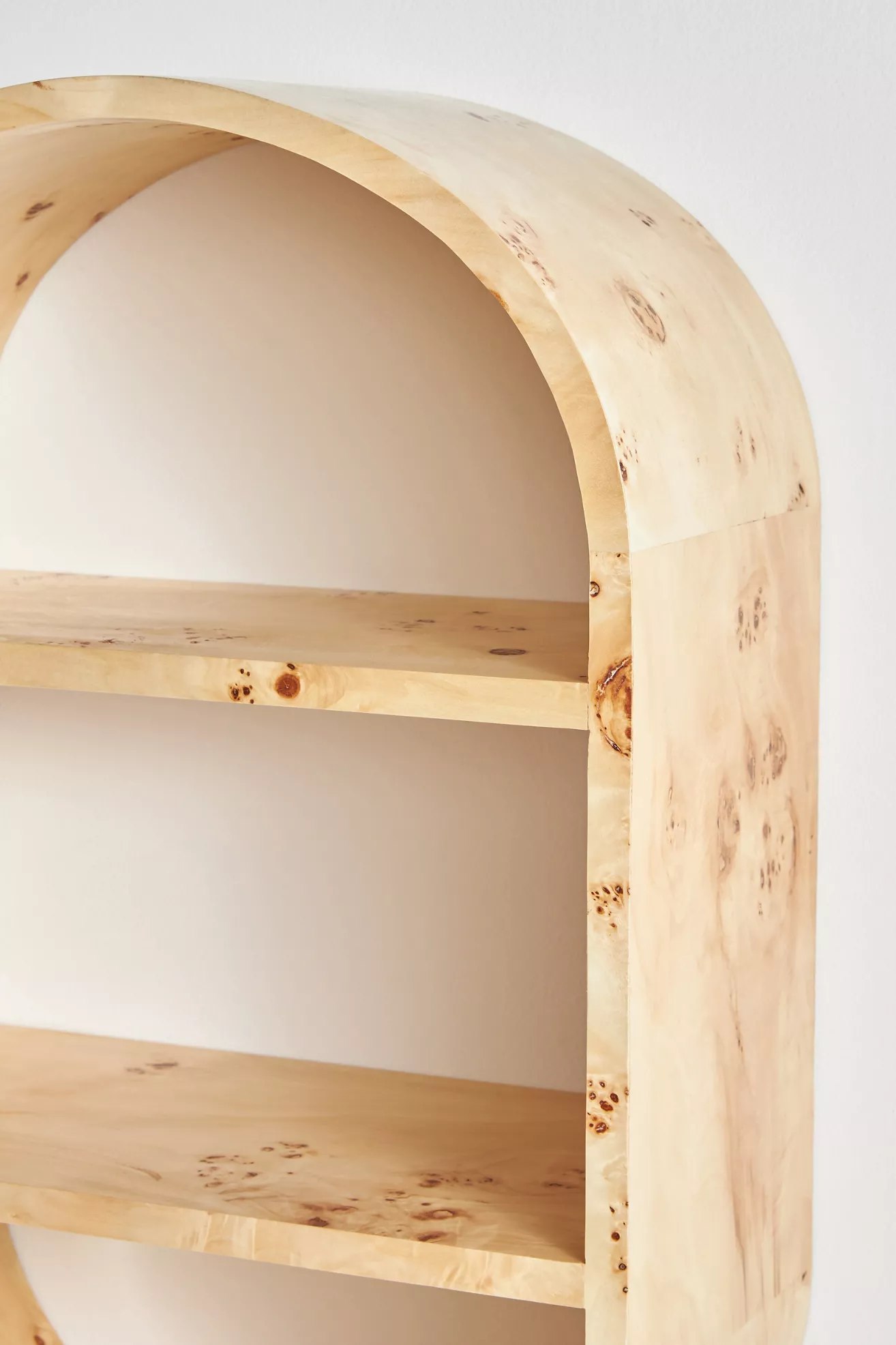 Close-up of a light wood open shelving unit with rounded top corner