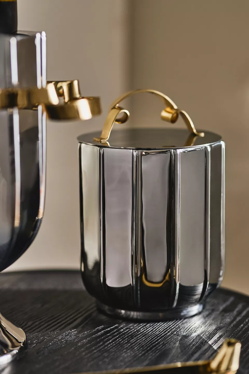 A dark silver ice bucket with a gold handle