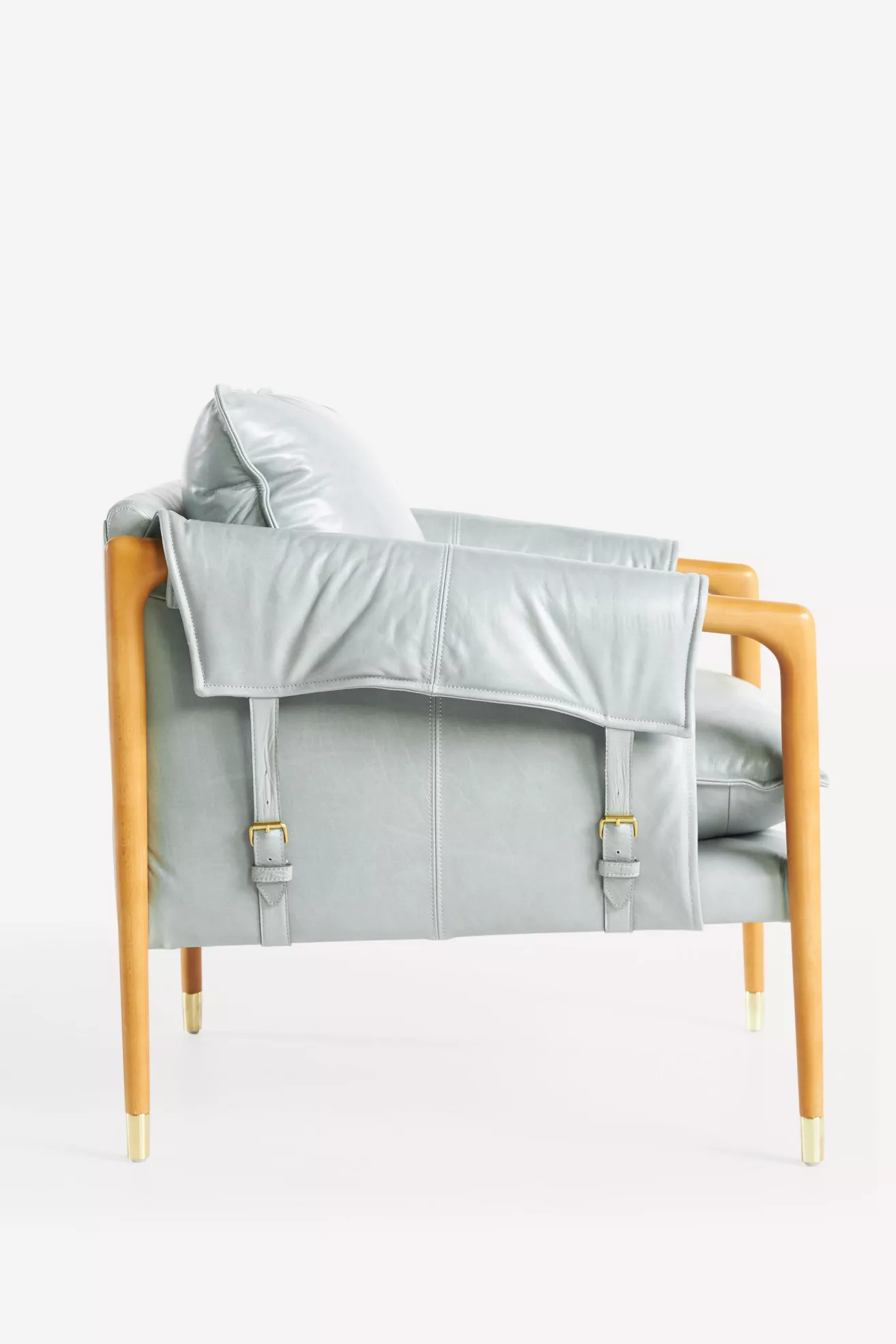 Back/side view of Havana leather armchair with strap hardware and light gray upholstery