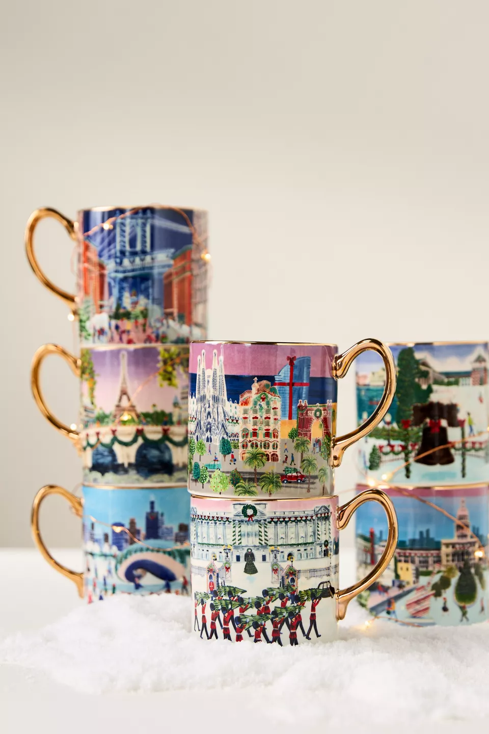 Seven mugs with holiday city scenes on them