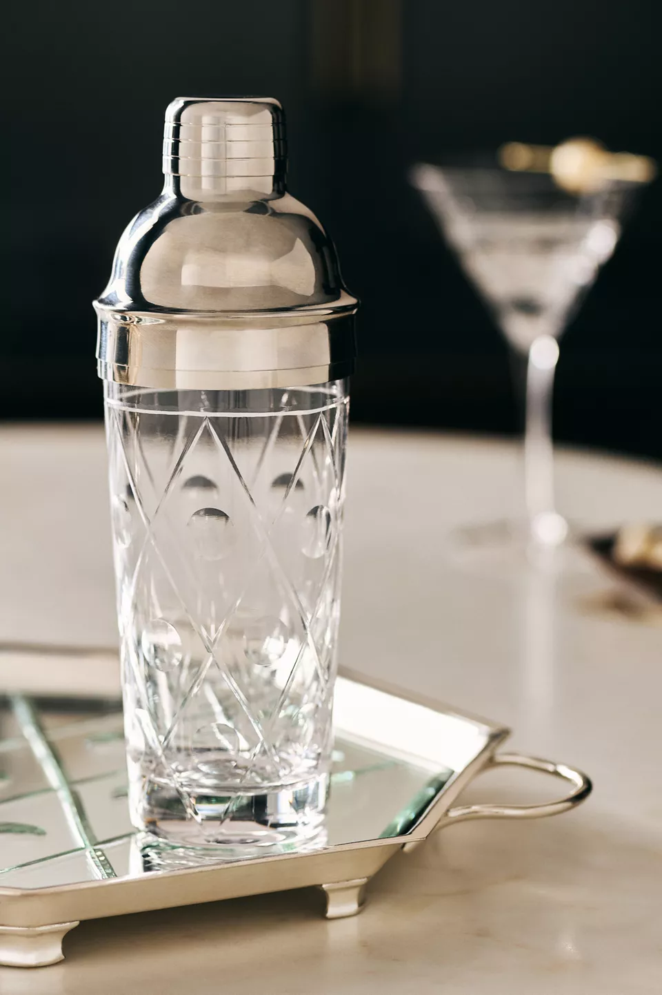 A clear and silver cocktail shaker on a silver tray