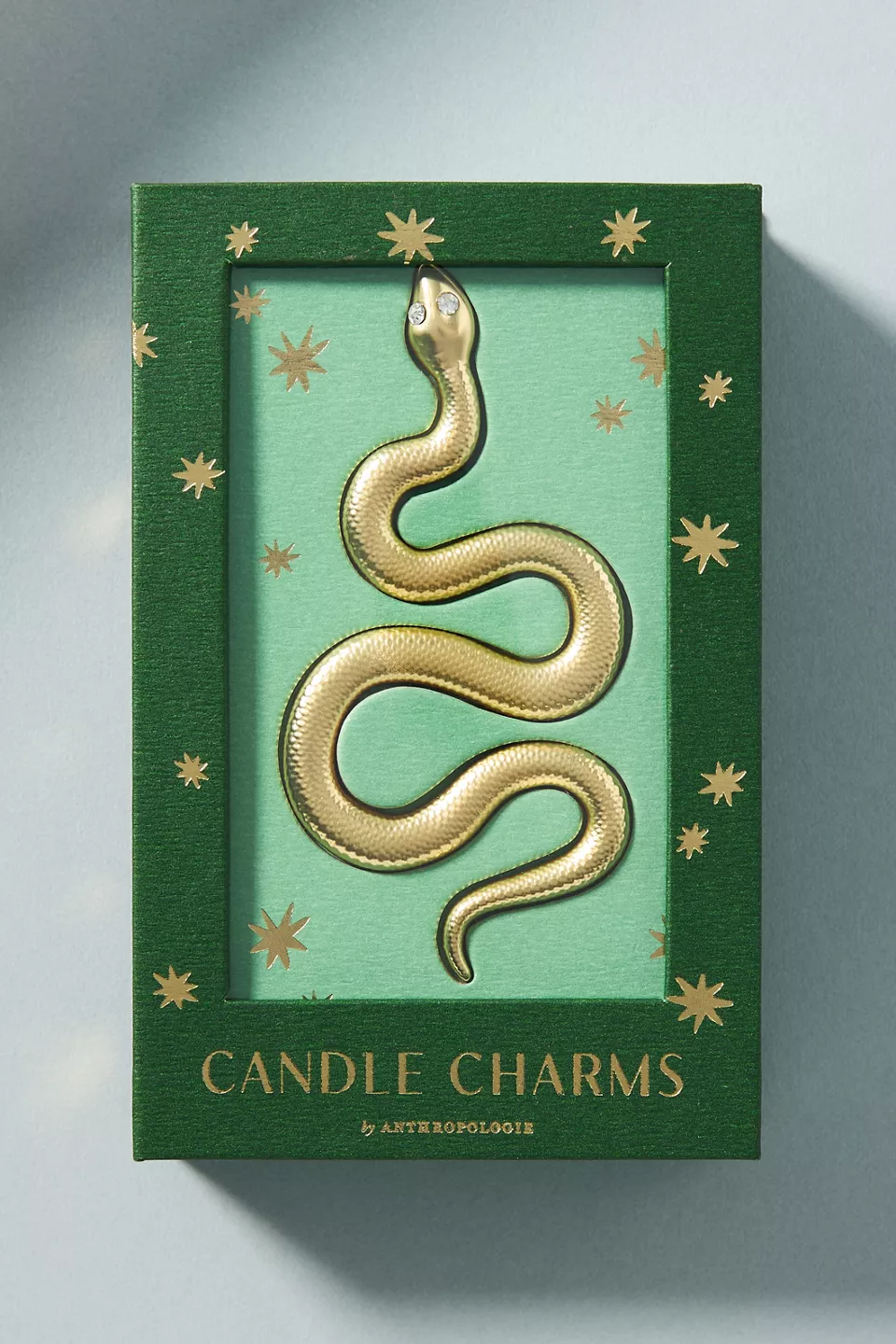 A gold snake candle charm in a green box