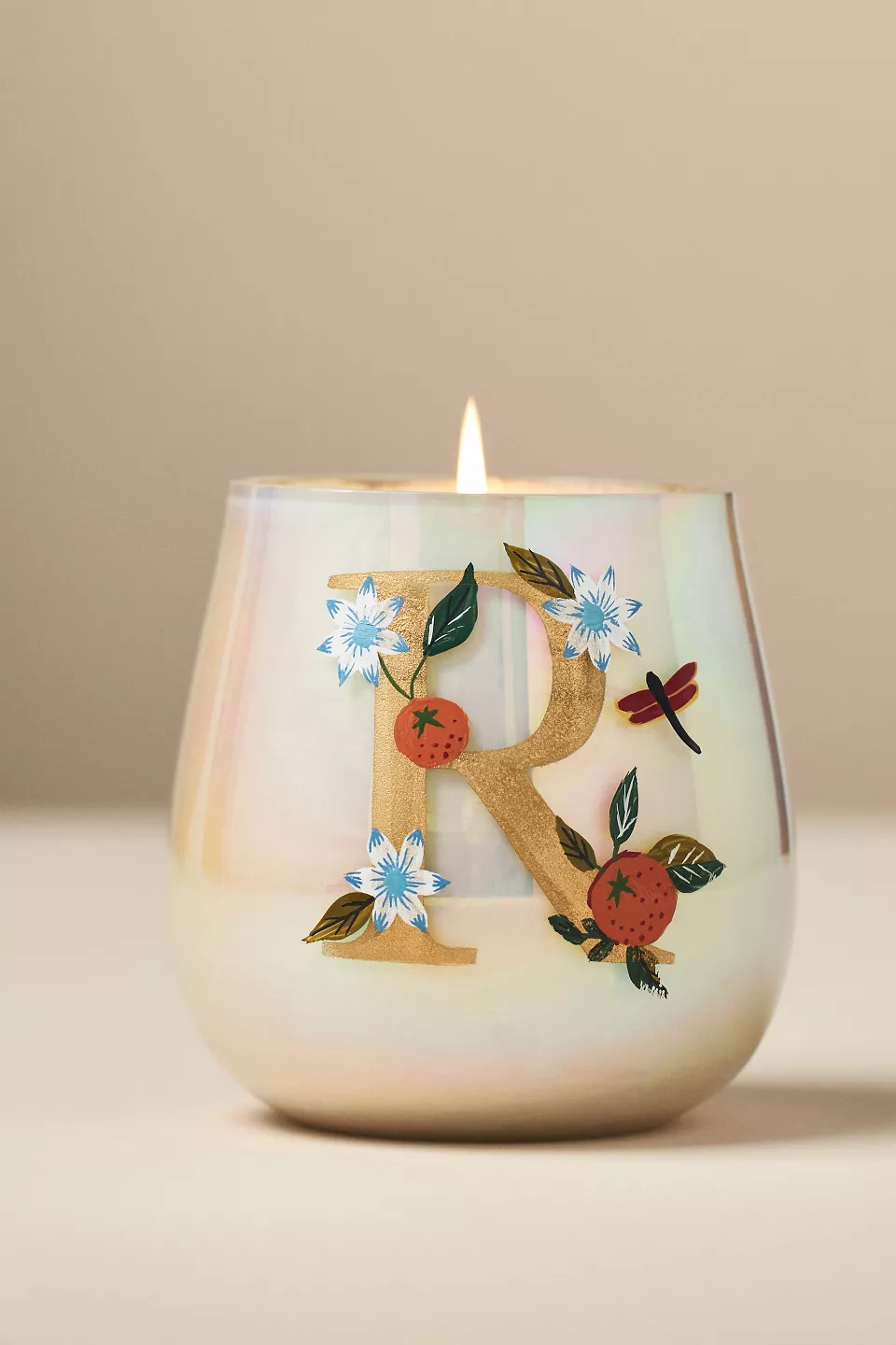 A candle in a glass with an R on it