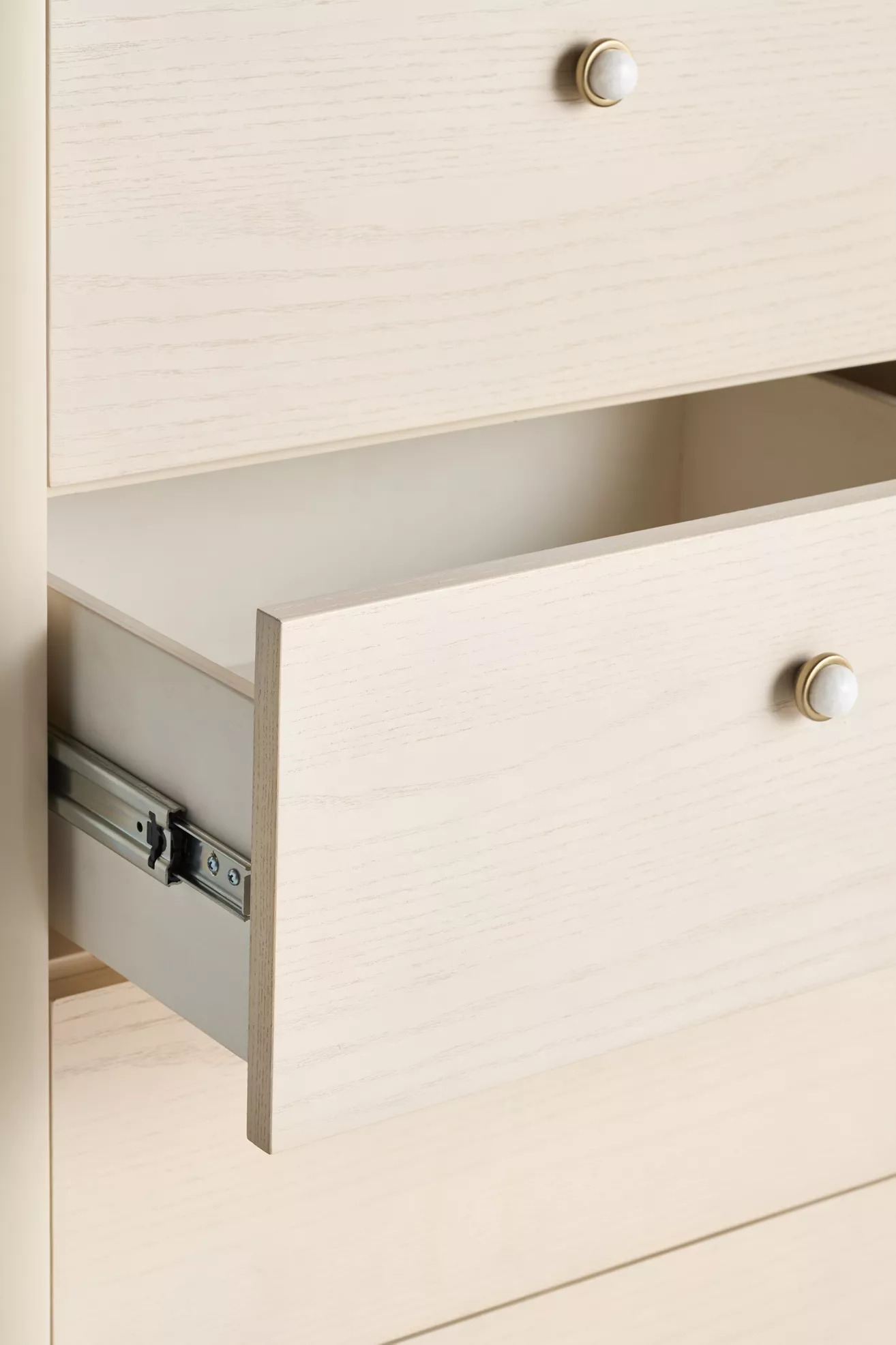 Close-up of a light wood dresser drawer with a white knob